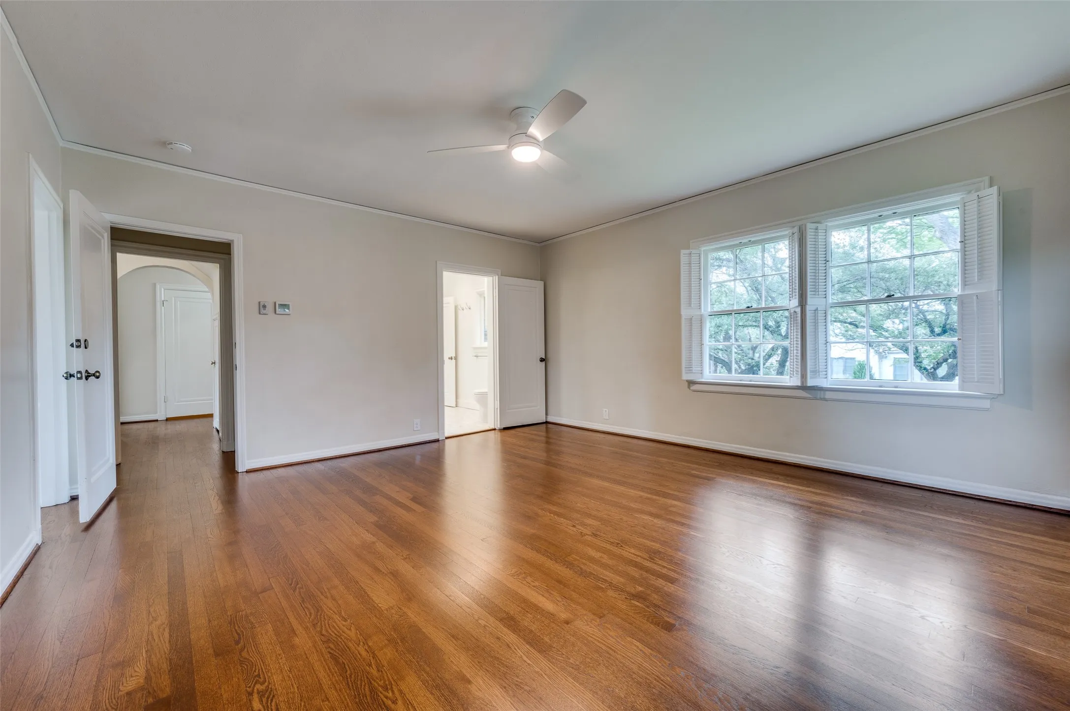 Large bedroom with abundant sunlight and just refinished hardwood floors.