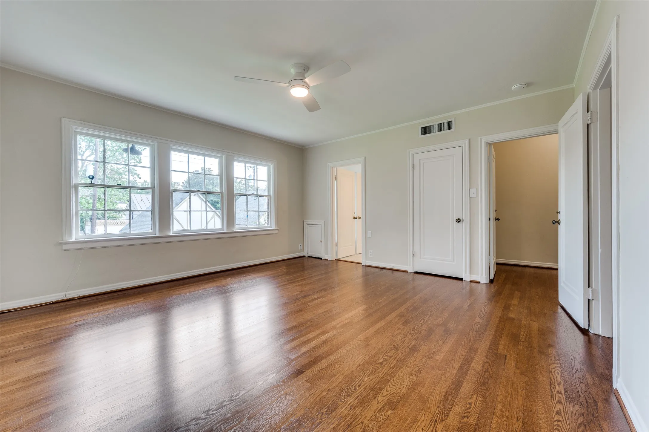 Large primary bedroom with abundant sunlight and just refinished hardwood floors.