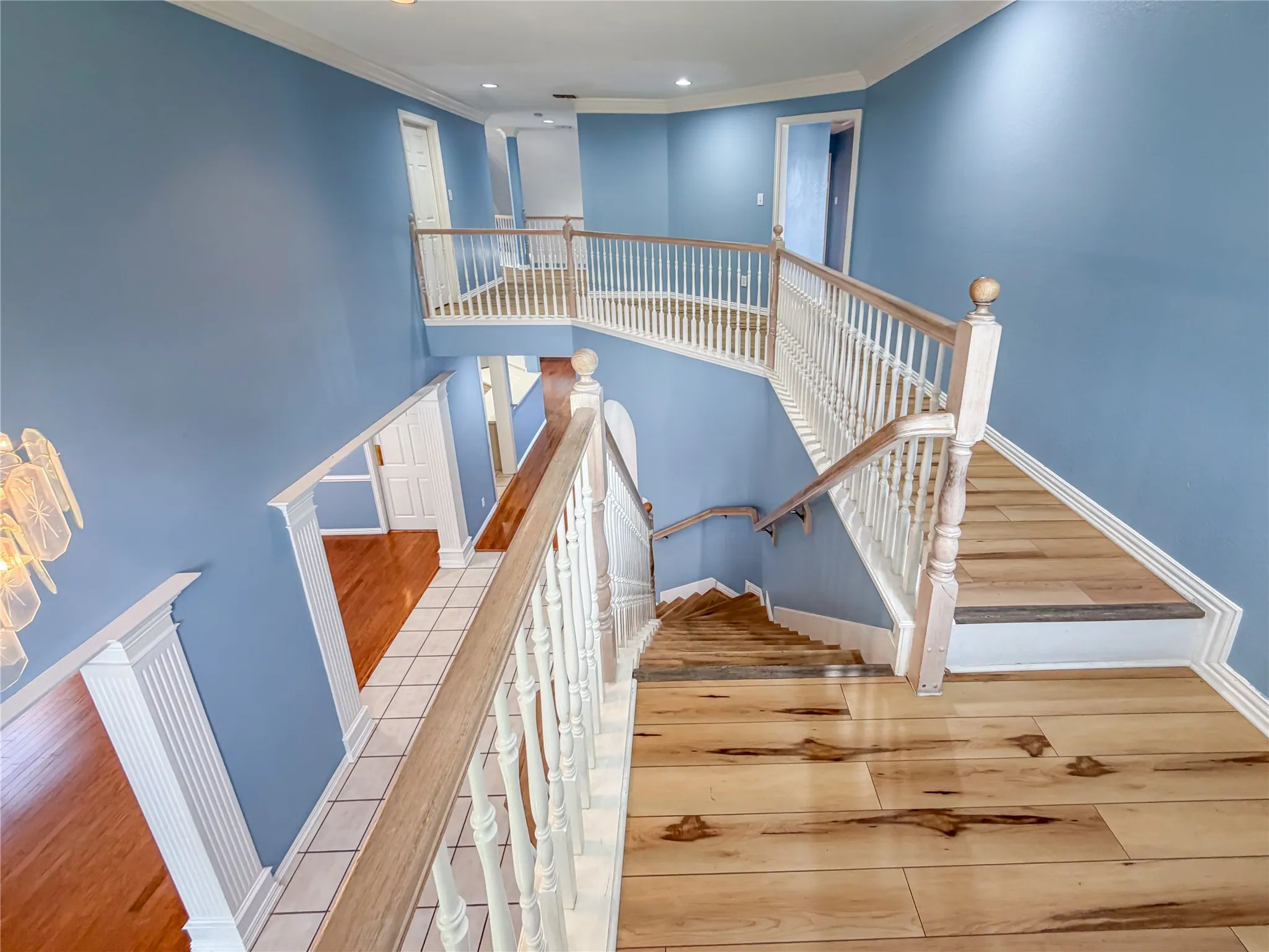 Multi-level staircase featuring light wood-finish flooring, white balusters, and light wood handrails