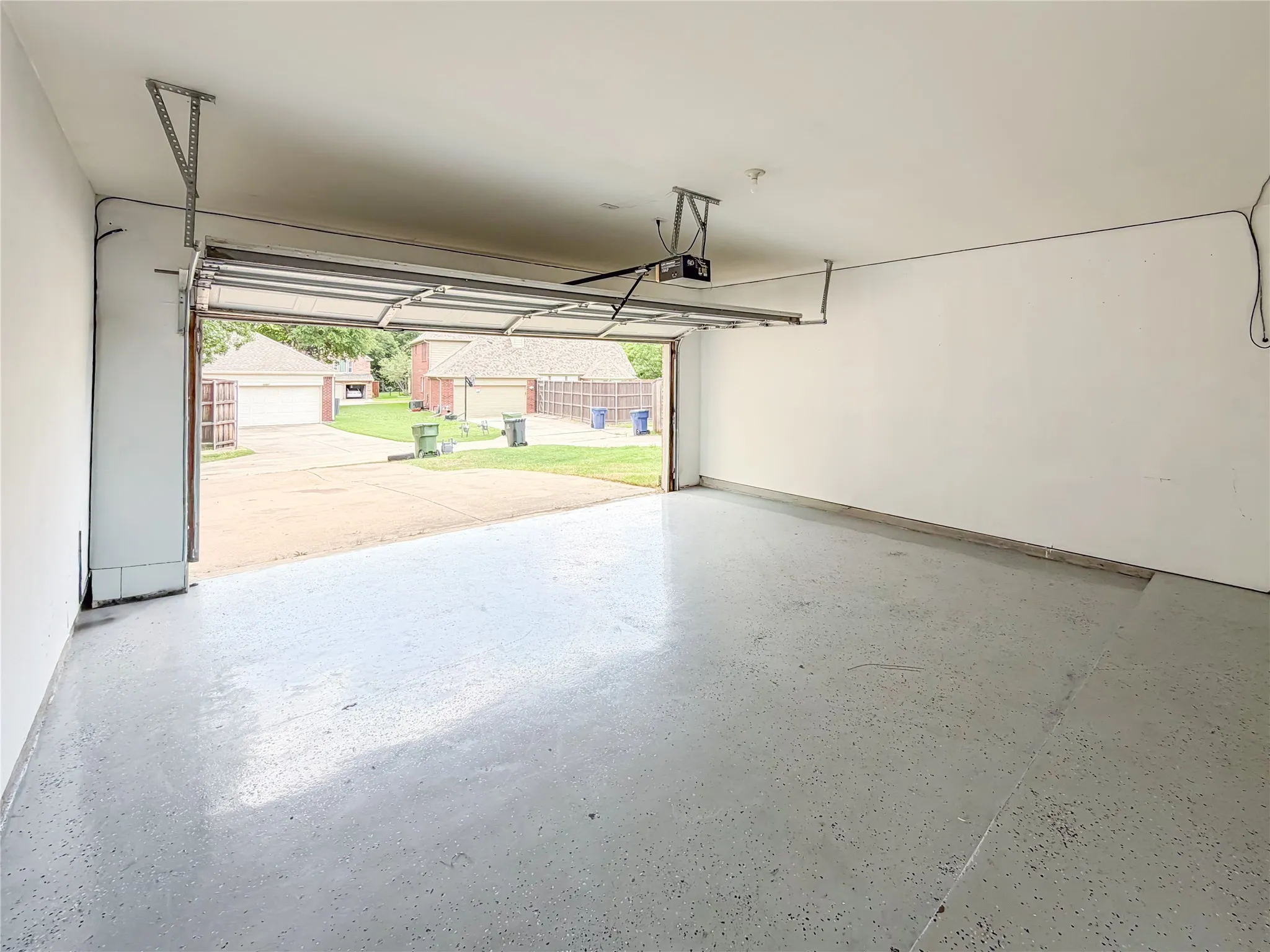 Garage space featuring a speckled epoxy floor coating, white painted walls, and an automatic garage door opener system