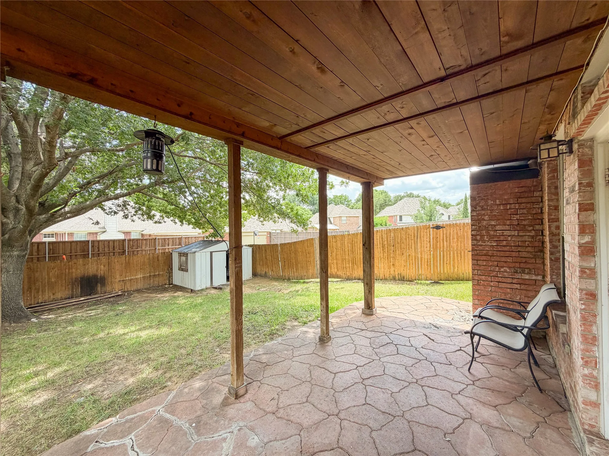Covered patio featuring a wood-finish ceiling, stamped concrete flooring, and exposed support beams