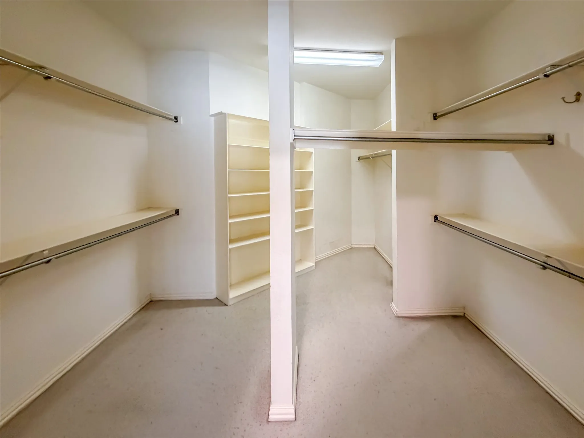 Walk-in closet featuring extensive built-in shelving, multiple hanging rods, and recessed lighting