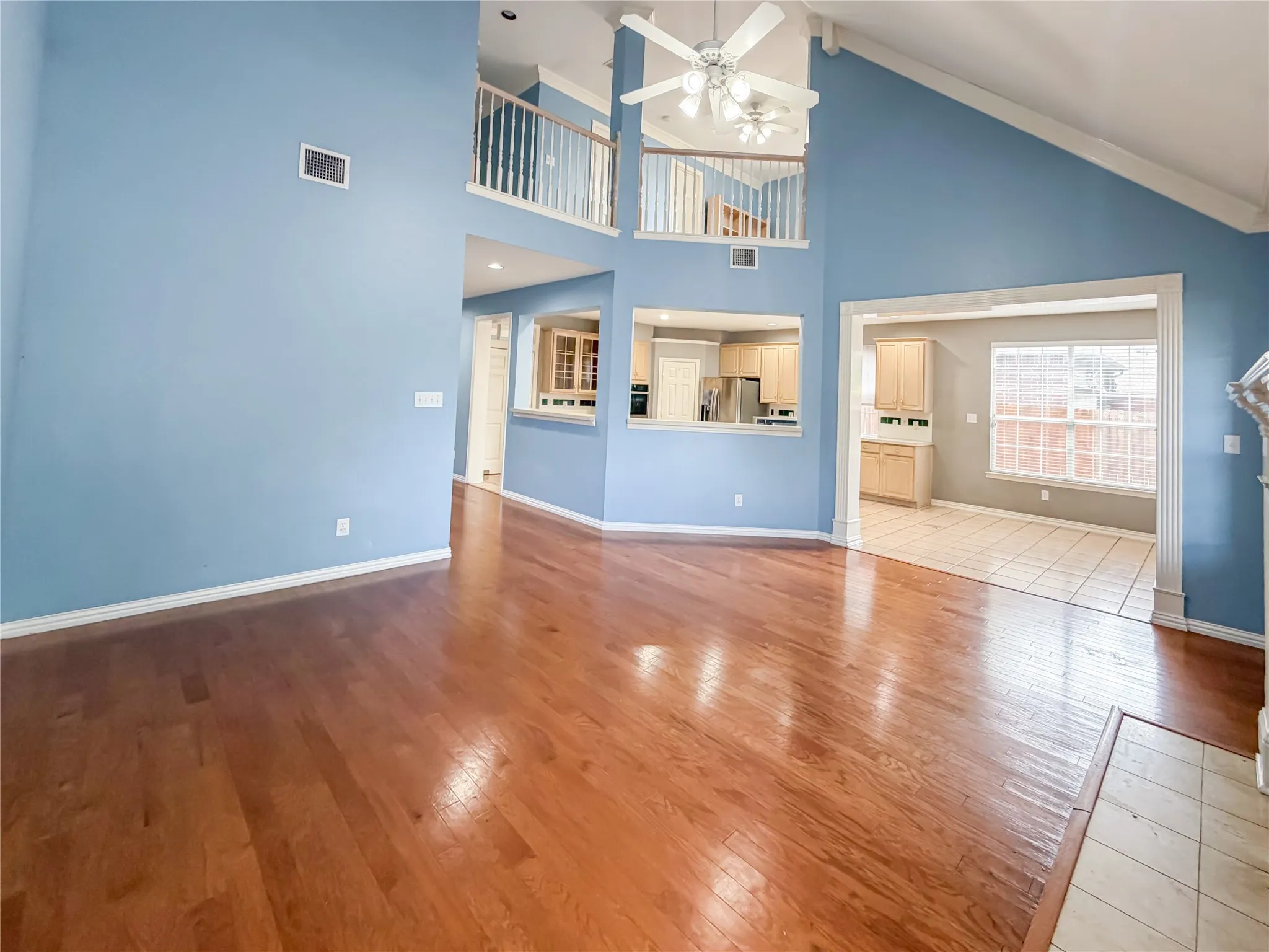 Expansive living area featuring vaulted ceilings, wood-finish flooring, and a second-story balcony overlook