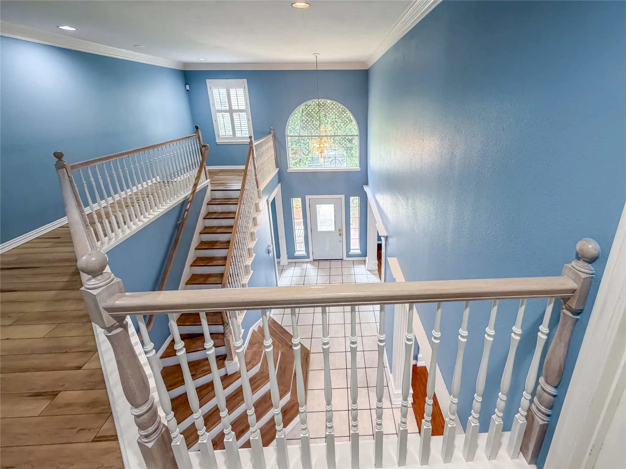 Two-story entry foyer with wood-finish flooring and staircase, featuring a large arched window