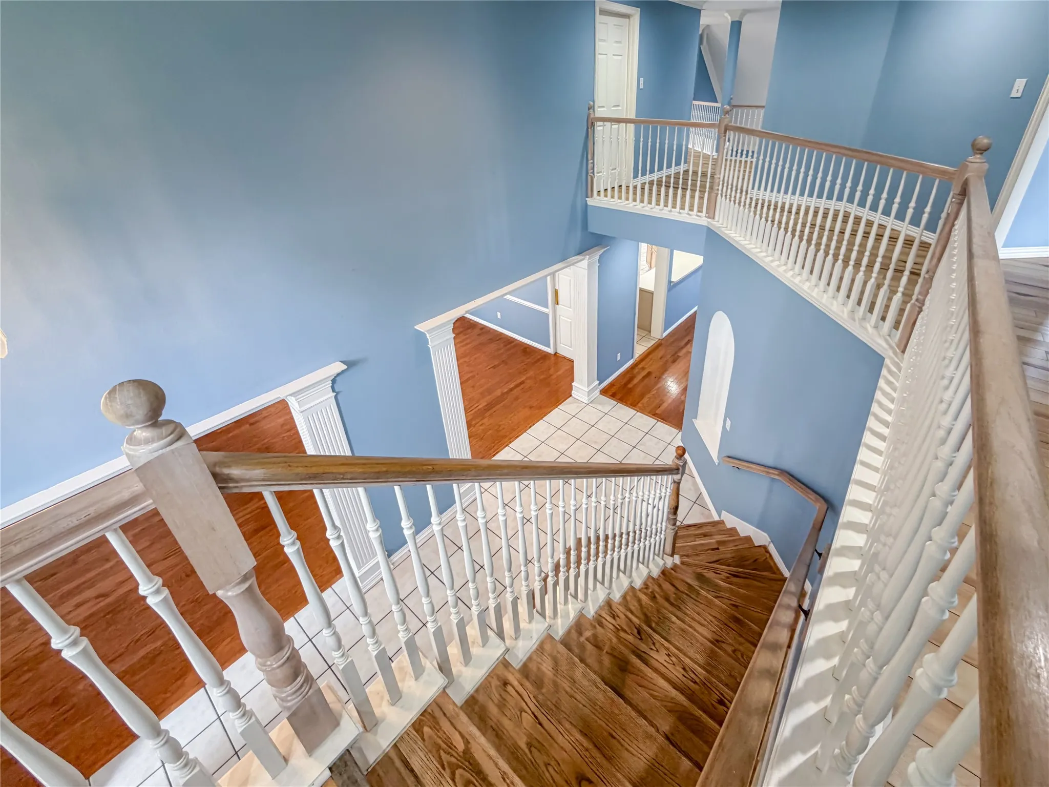 Grand staircase featuring wood-finish treads and balusters with white pickets