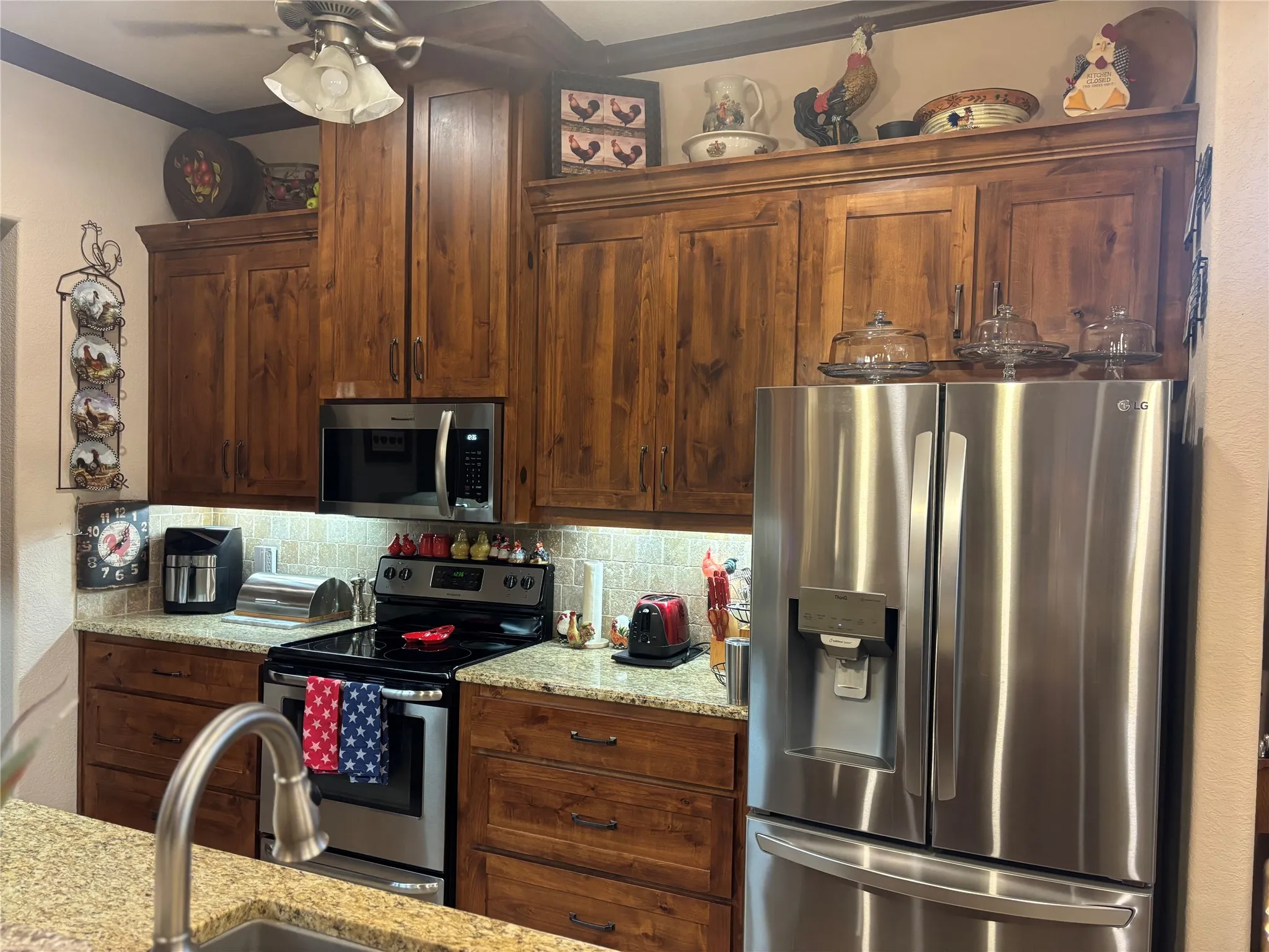 Kitchen featuring wood-finish cabinetry, stainless steel appliances, granite countertops, and a subway tile backsplash