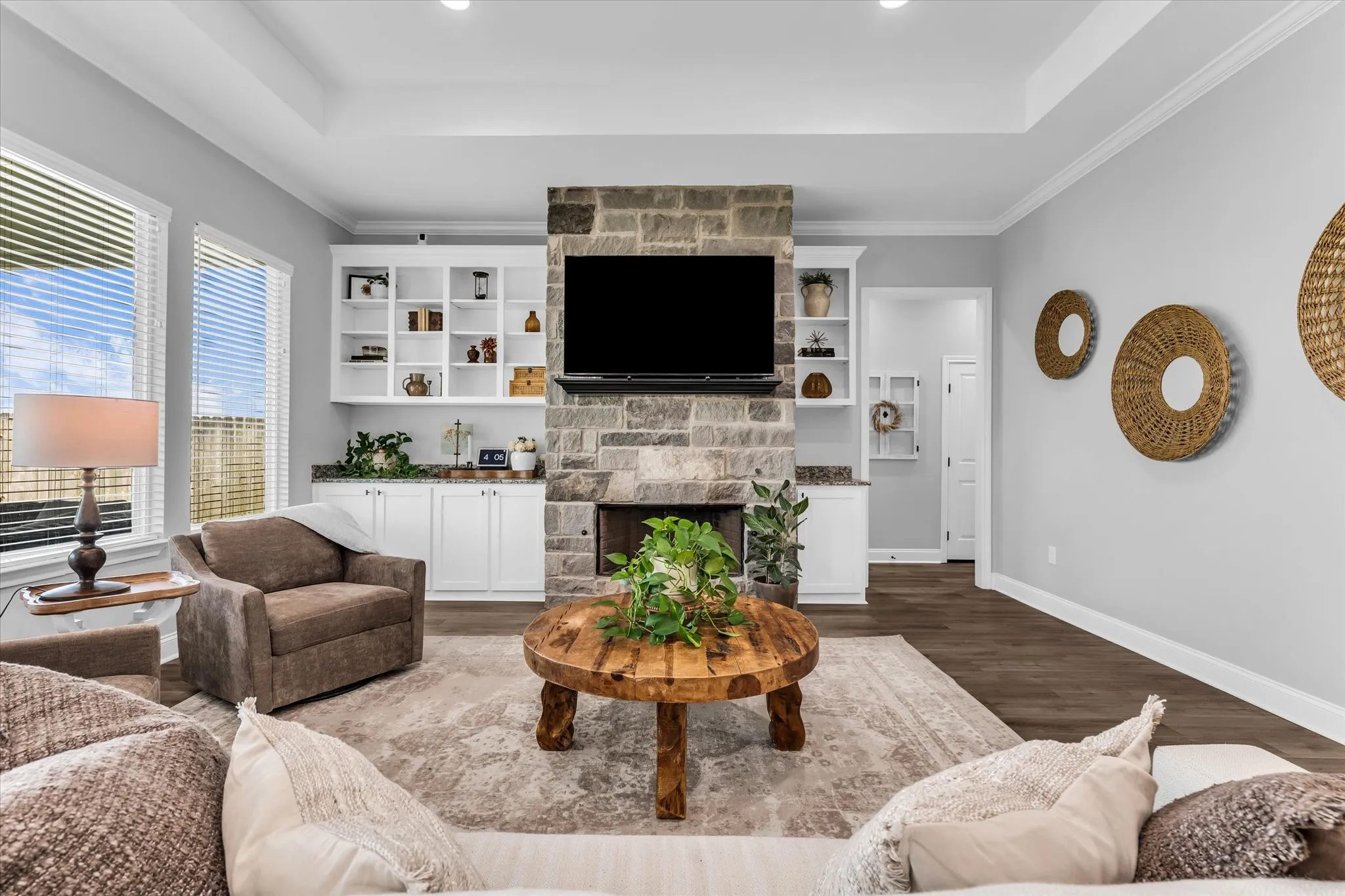 stone fireplace in living room with built ins and open layout to kitchen