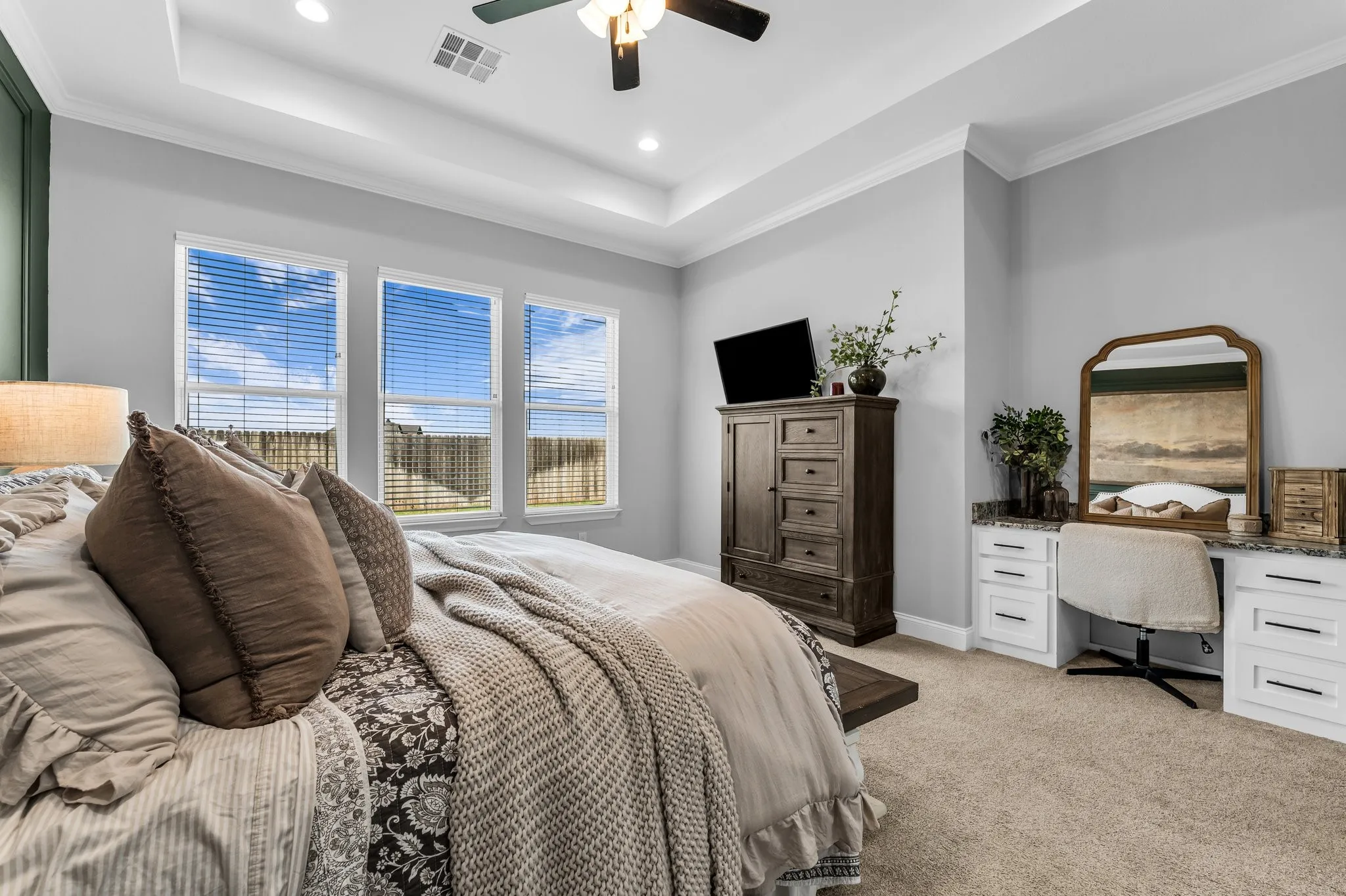 large primary bedroom with windows and built in desk