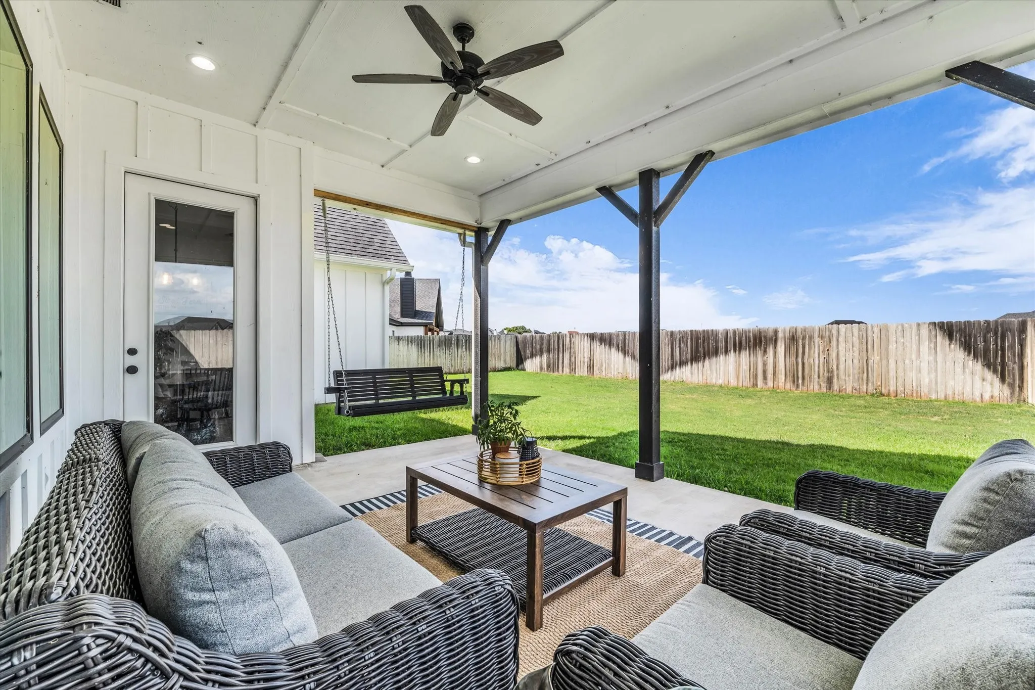 large covered back porch with swing; perfect for entertaining guests or relaxing while enjoying the view of the backyard