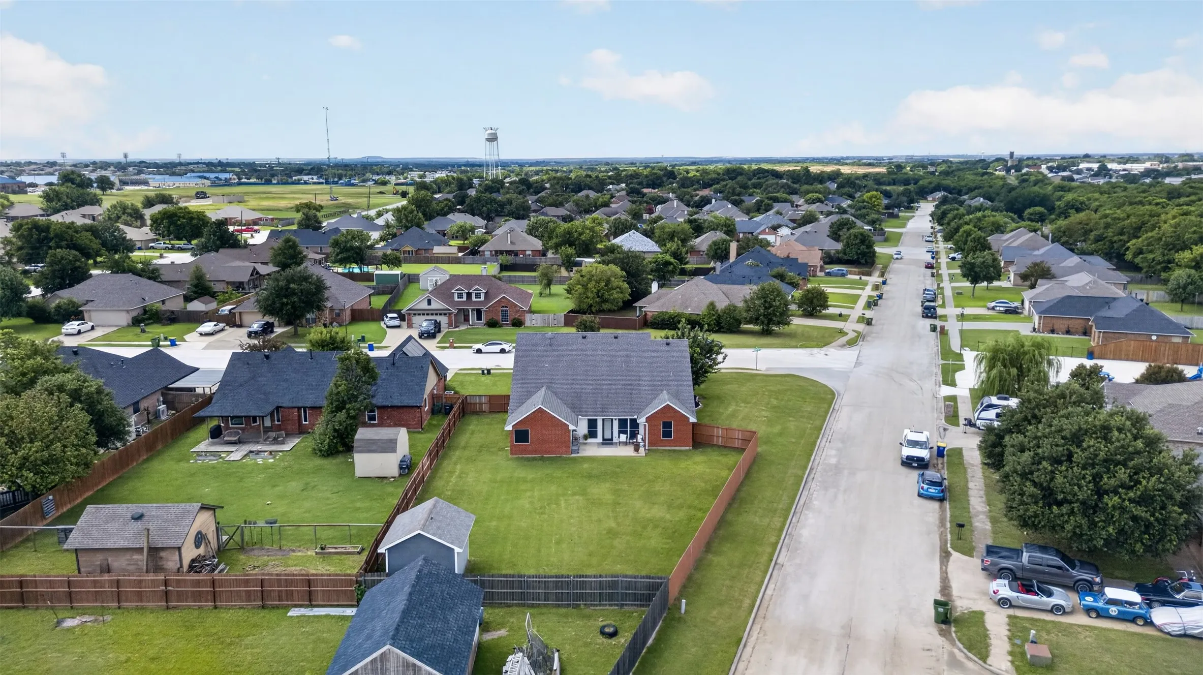 Residential neighborhood featuring an array of single-story homes with dark roofs and mature trees lining the streets