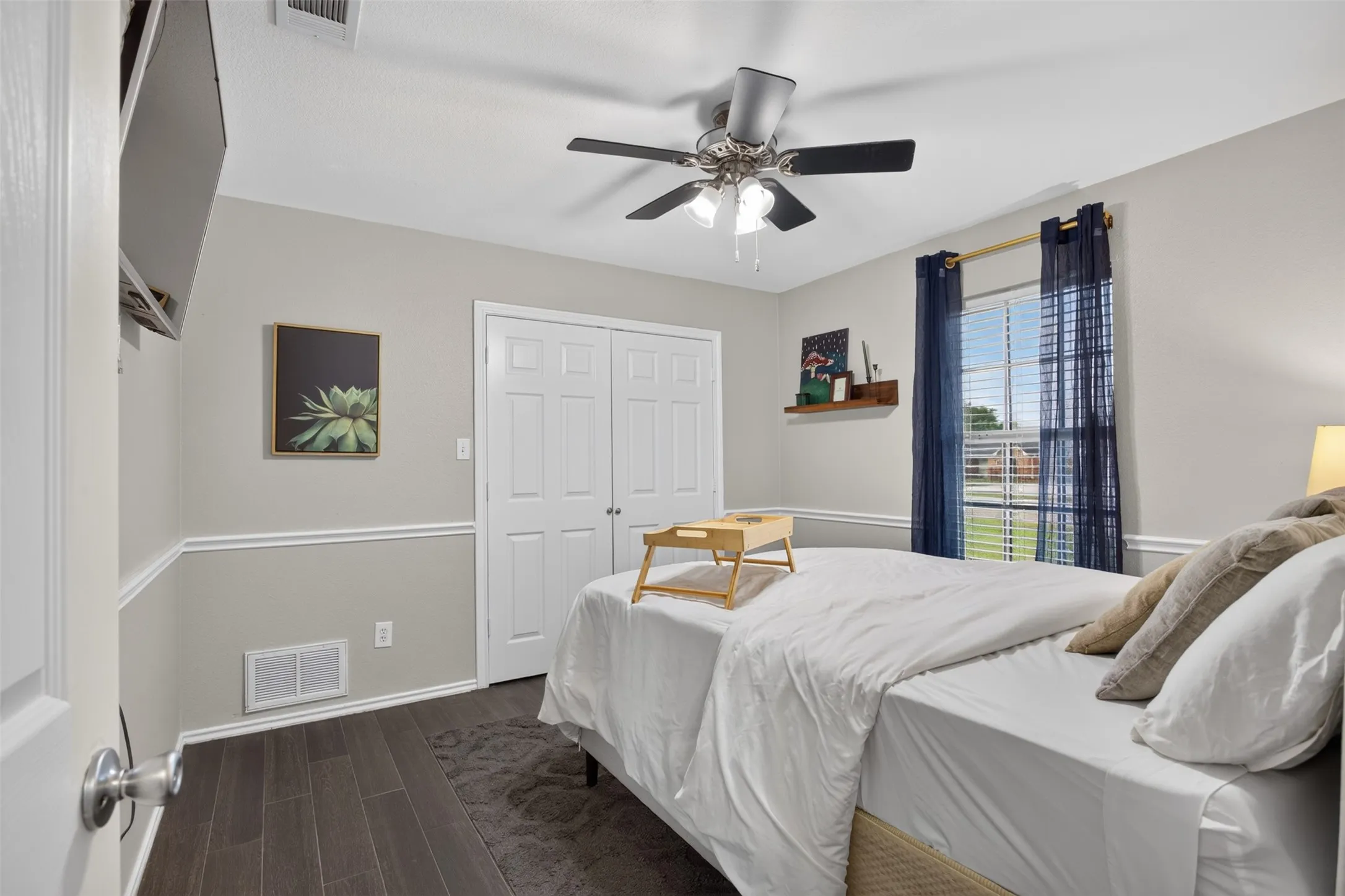 Bedroom featuring wood-finish flooring, white trim, a double-door closet, and a ceiling fan with integrated lighting