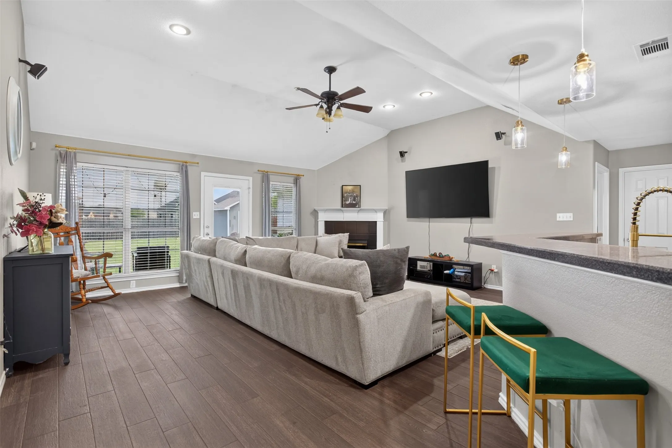 Vaulted ceiling living area featuring wood-finish flooring, a white mantel fireplace, and recessed lighting