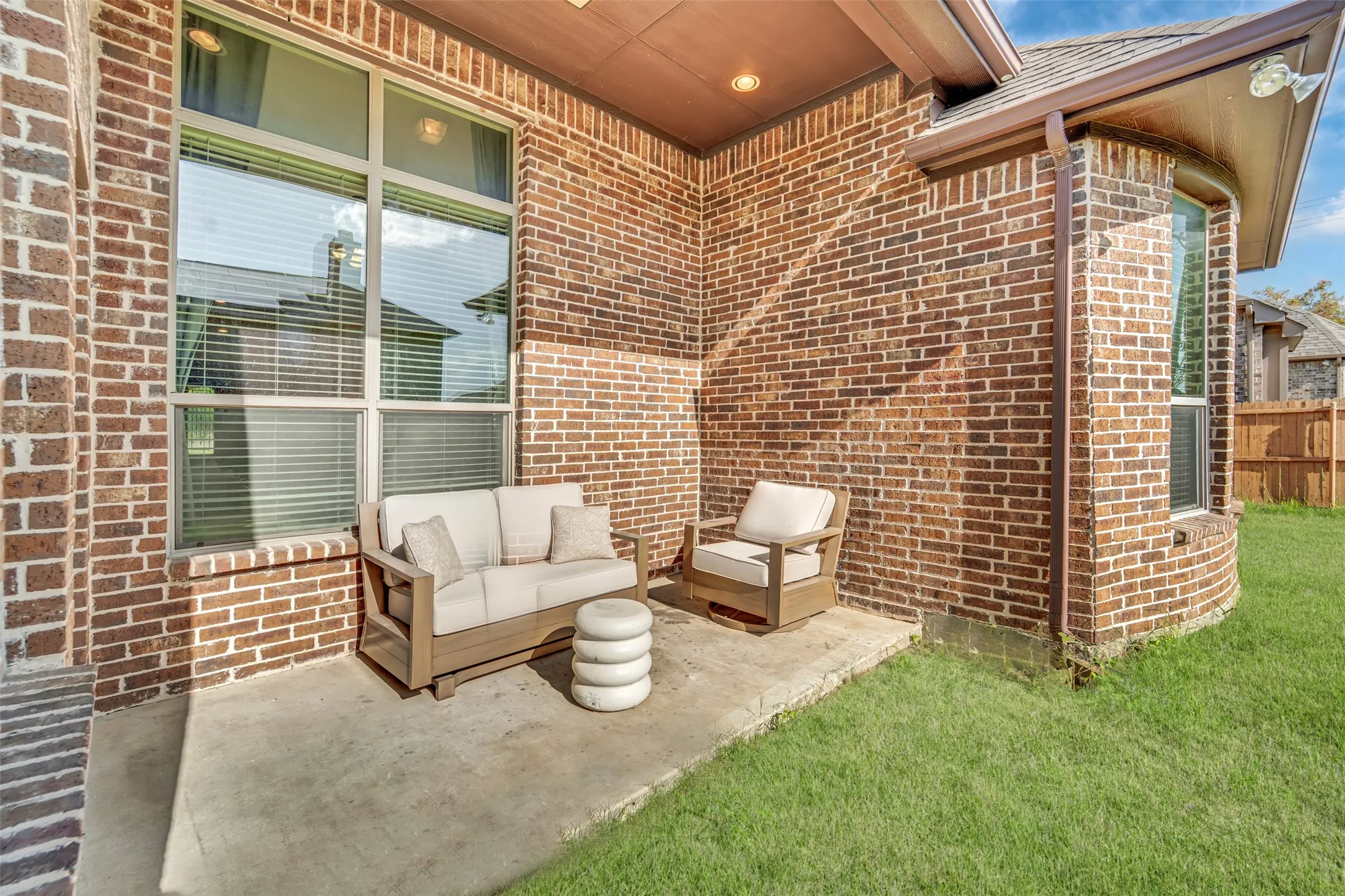 Private concrete patio featuring a full brick exterior and a curved bay window