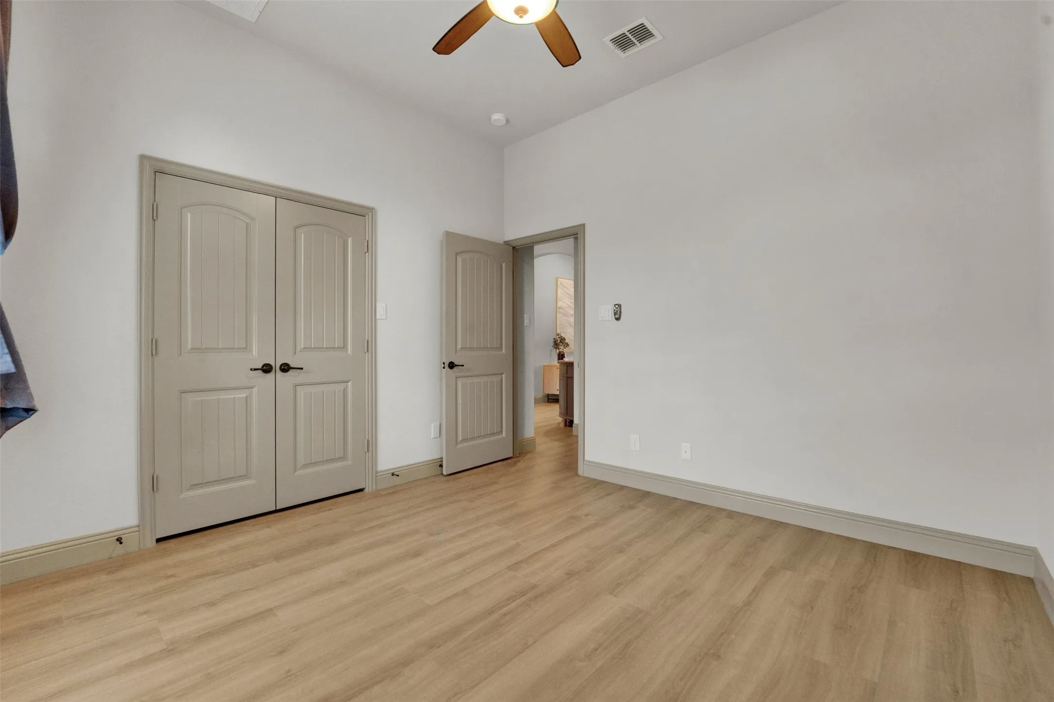 Room featuring wood-finish flooring, light neutral wall paint, and a ceiling fan