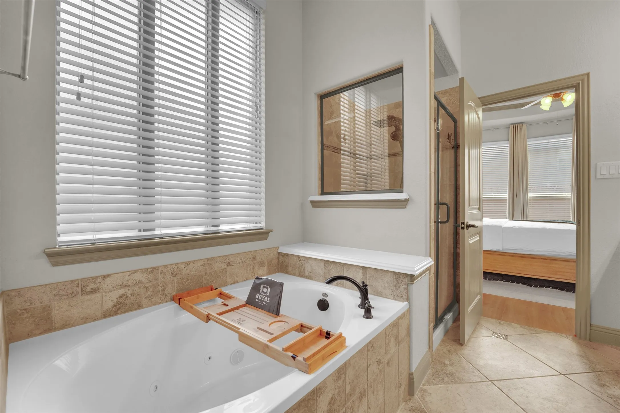 Jetted soaking tub with a bronze-finish faucet, surrounded by natural stone tile