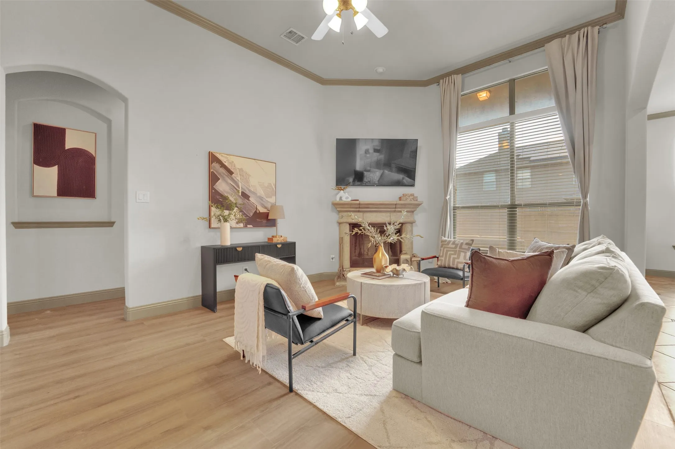 Living area featuring an ornate fireplace, wood-finish flooring, and a large window with blinds