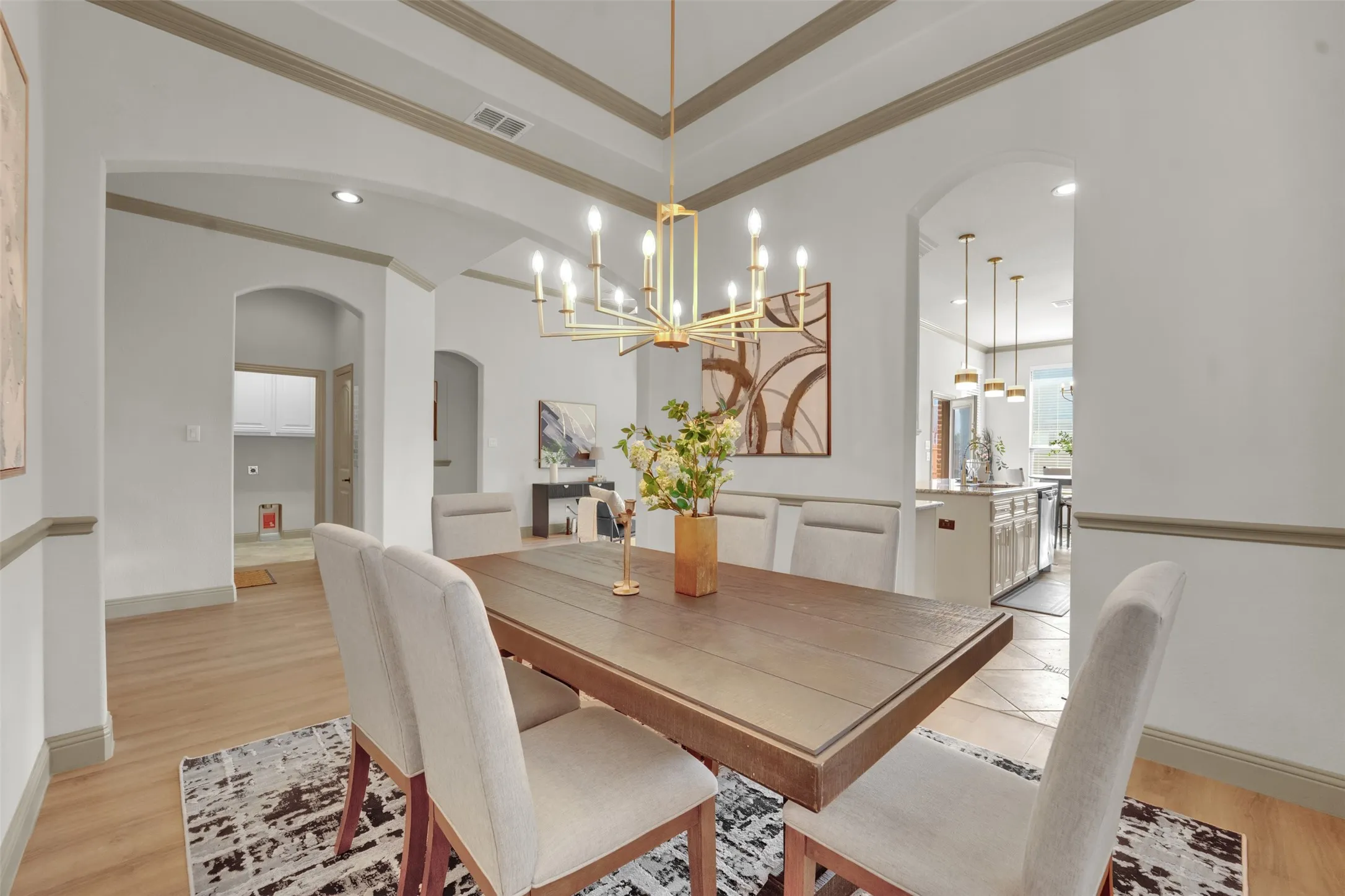 Dining area featuring a coffered ceiling with crown molding, wood-finish flooring, a contemporary chandelier, and arched doorways