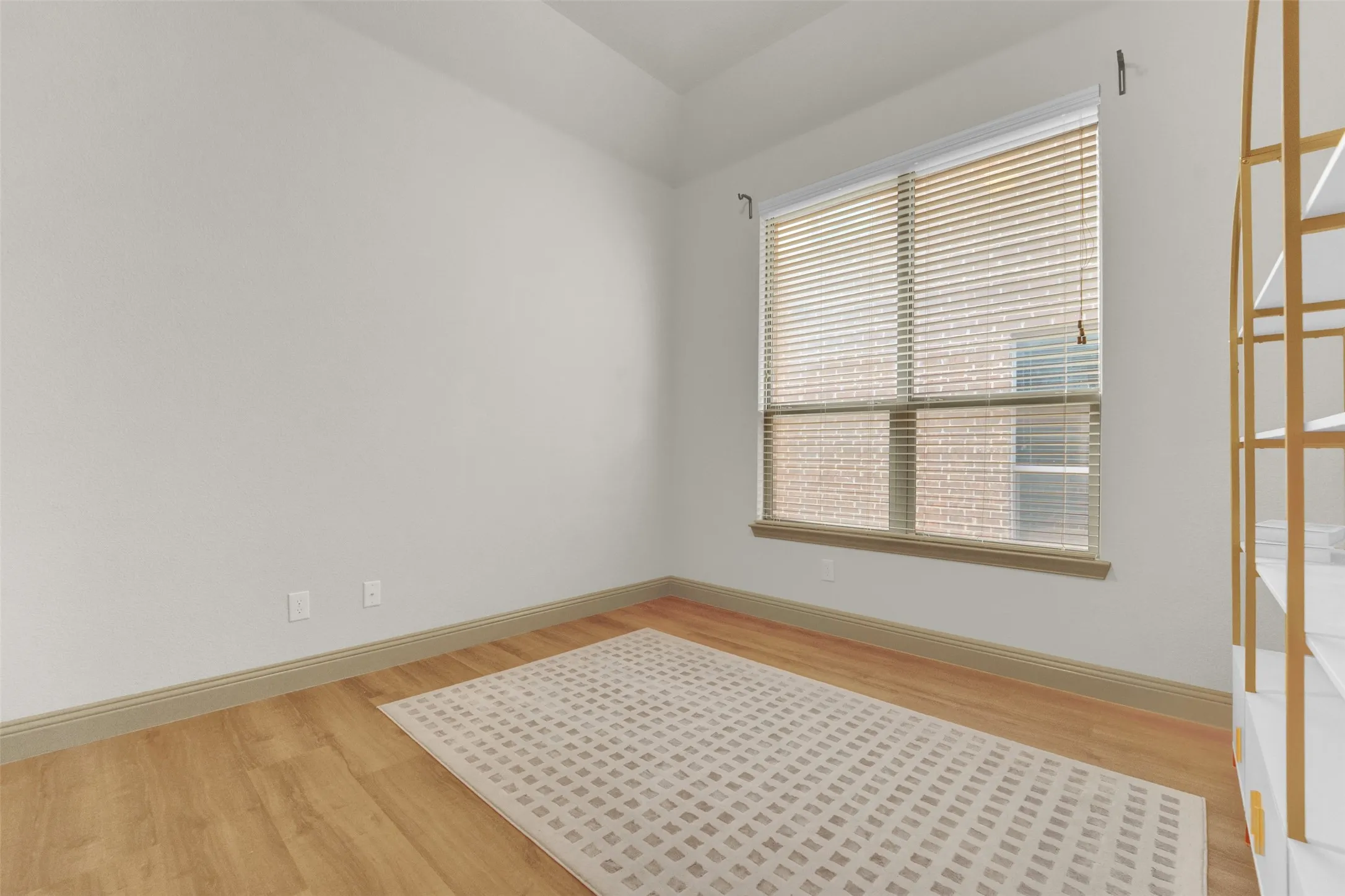 Room with a single window featuring horizontal blinds, wood-finish flooring, and white painted walls