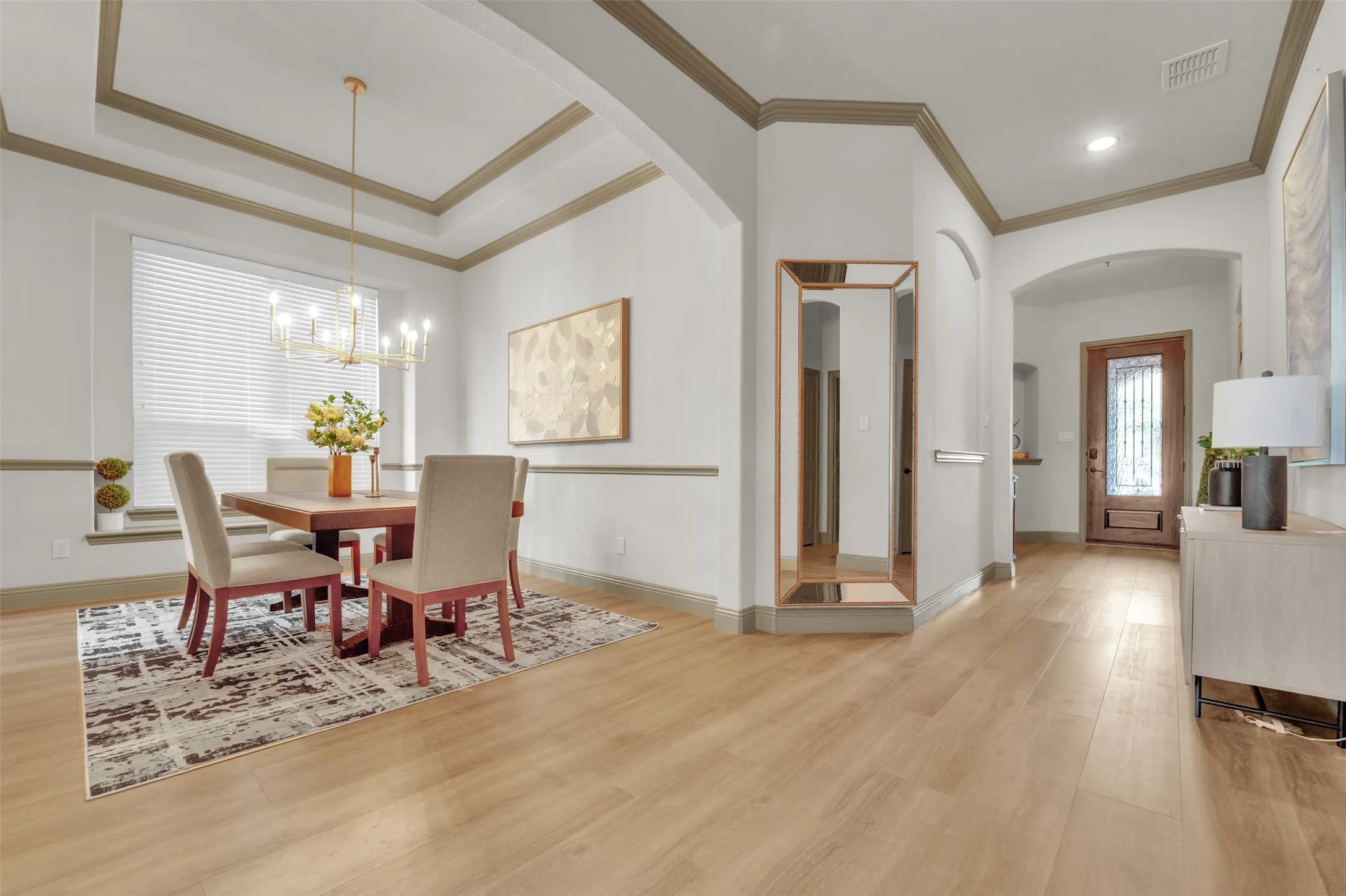 Dining area featuring wood-finish flooring, a tray ceiling with crown molding, and a chandelier