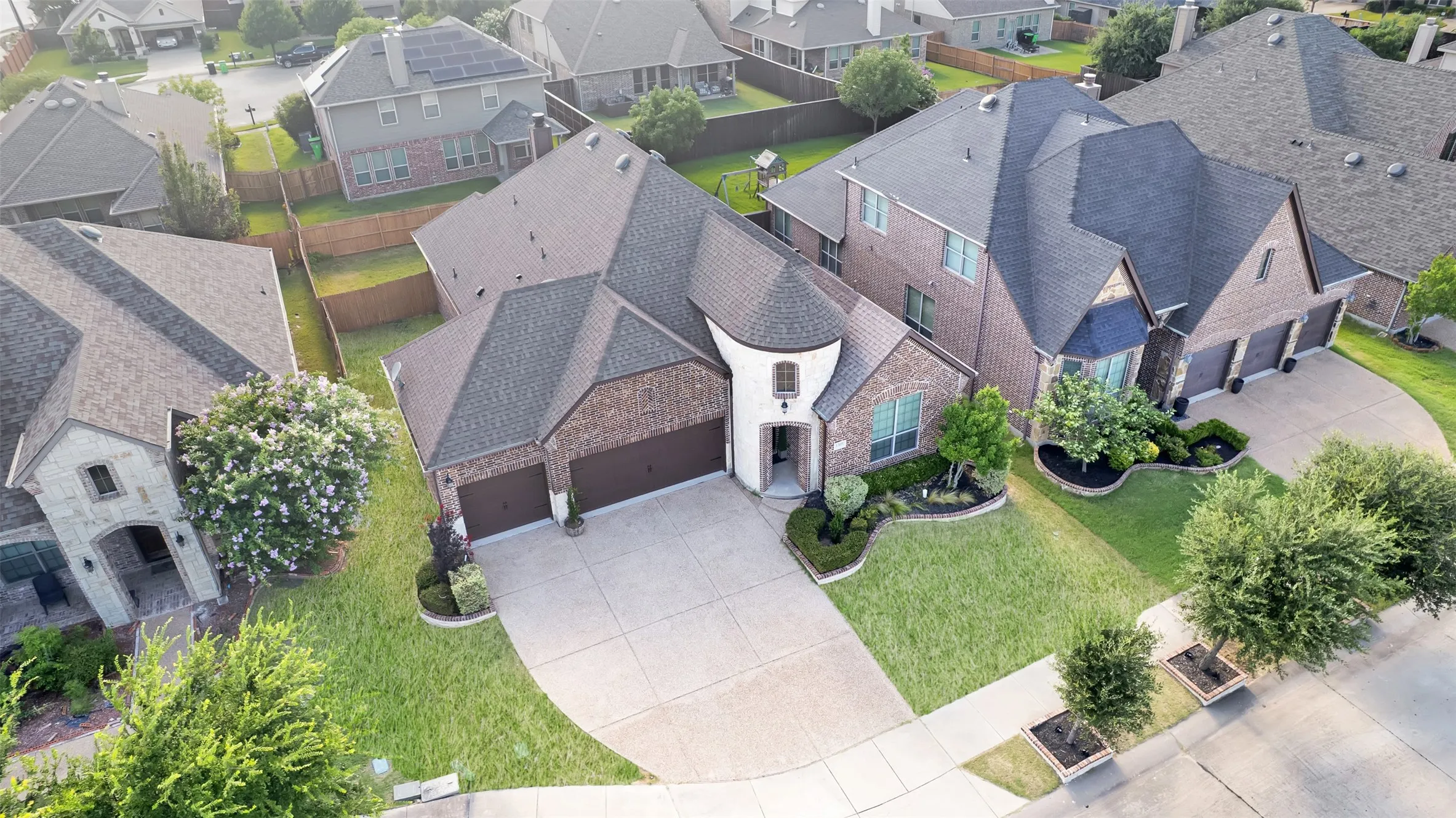 Brick and stone facade residence featuring a two-car garage, manicured front landscaping, and a concrete driveway