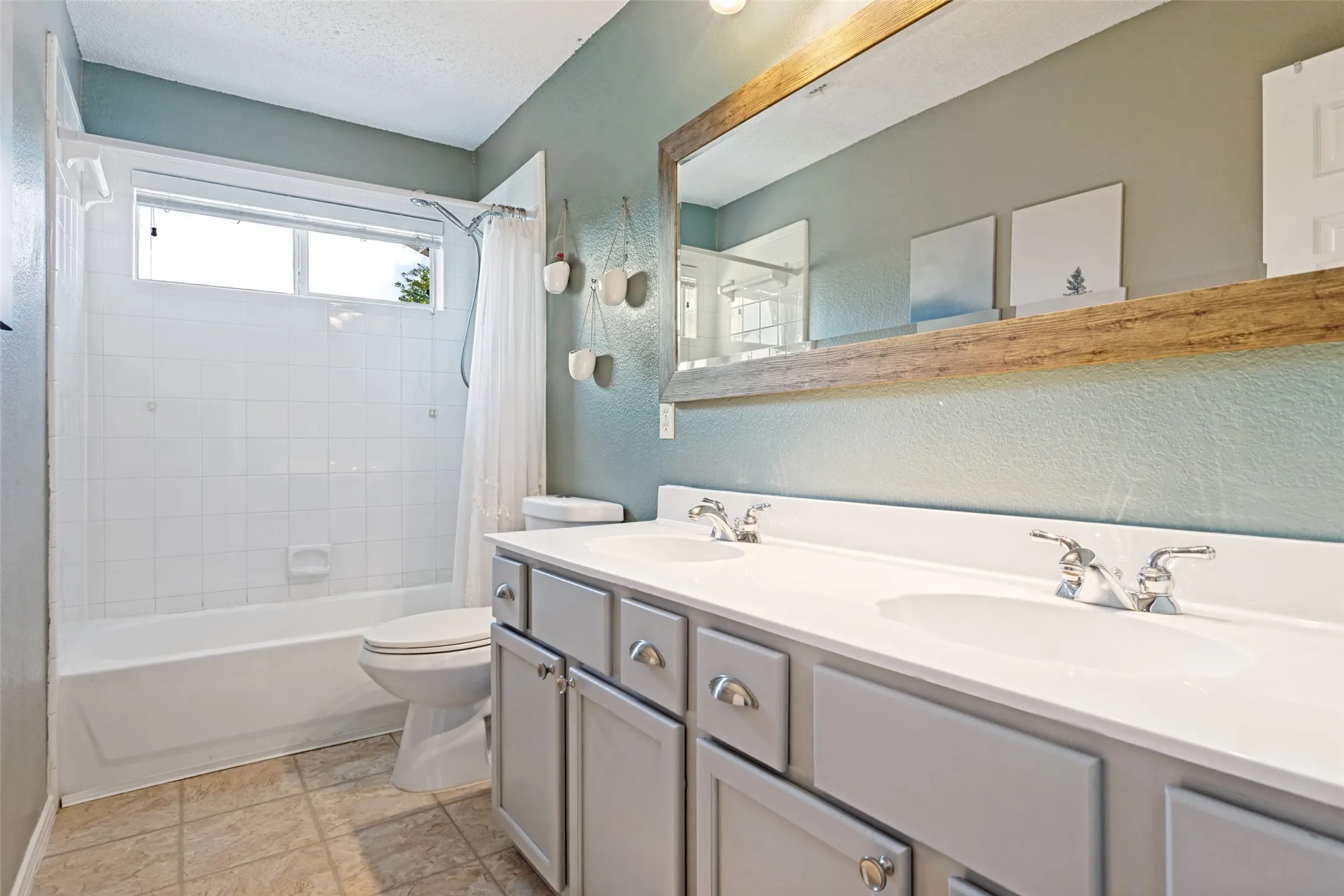 Bathroom featuring a dual vanity with light gray cabinetry, chrome fixtures, and a white countertop