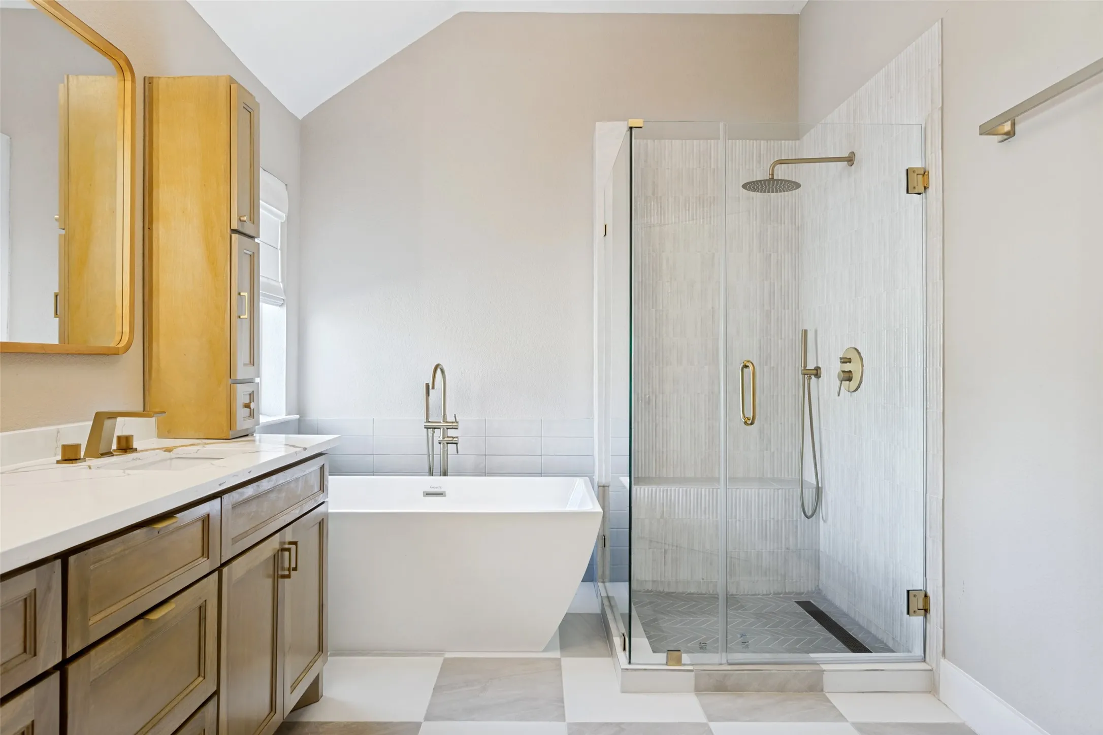Spacious bathroom featuring a freestanding soaking tub, glass-enclosed shower with rain head, dual vanity with undermount sinks, and checkered floor tiling