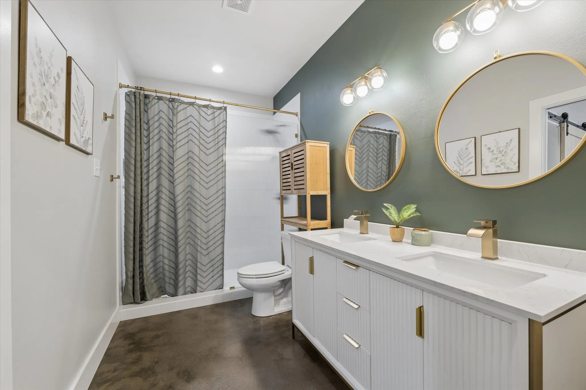 Bathroom featuring a dual vanity with white cabinetry, integrated sinks, and gold-finish fixtures