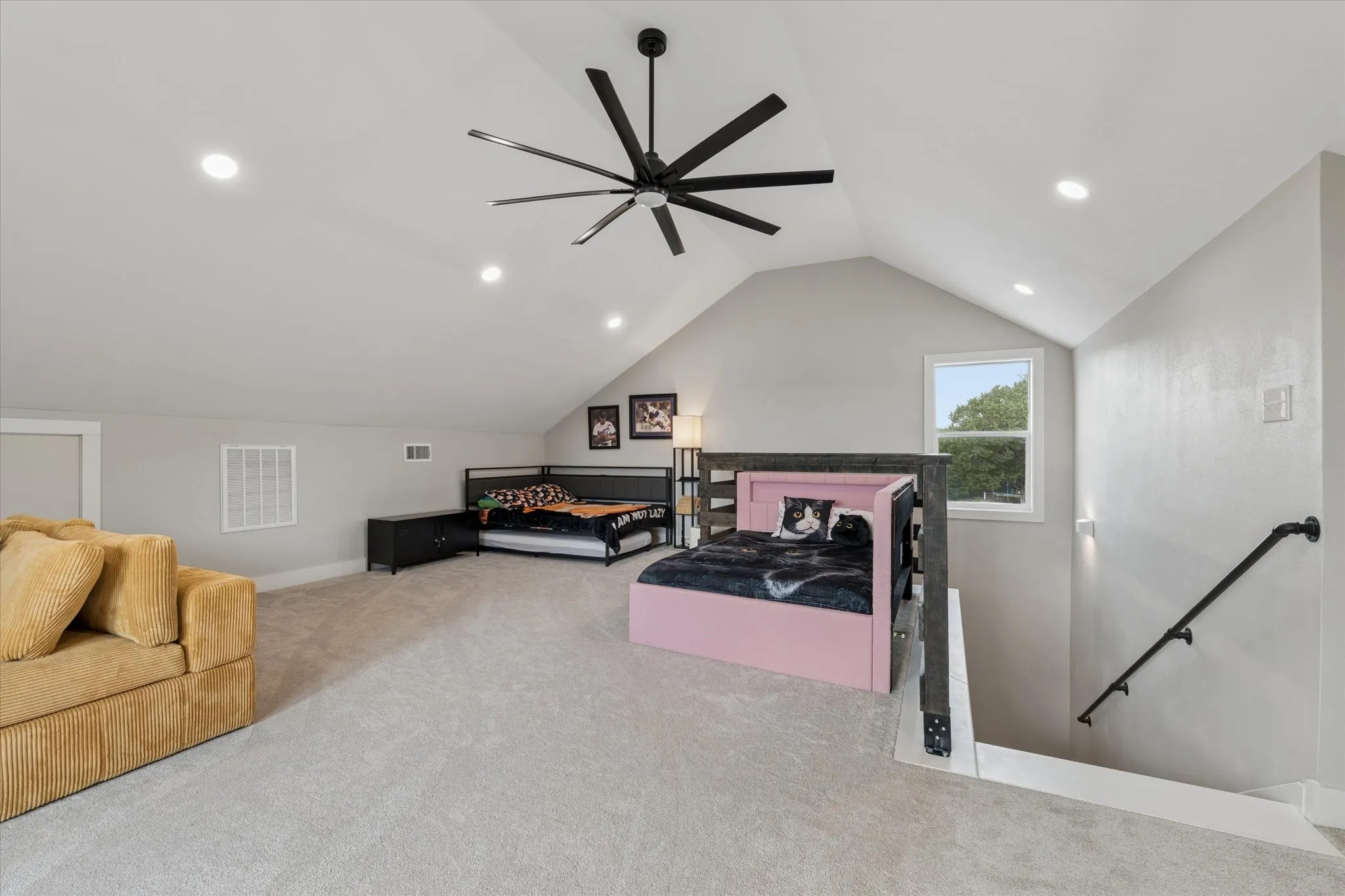 Spacious second-story room featuring a vaulted ceiling with a large ceiling fan, recessed lighting, and a window providing natural light