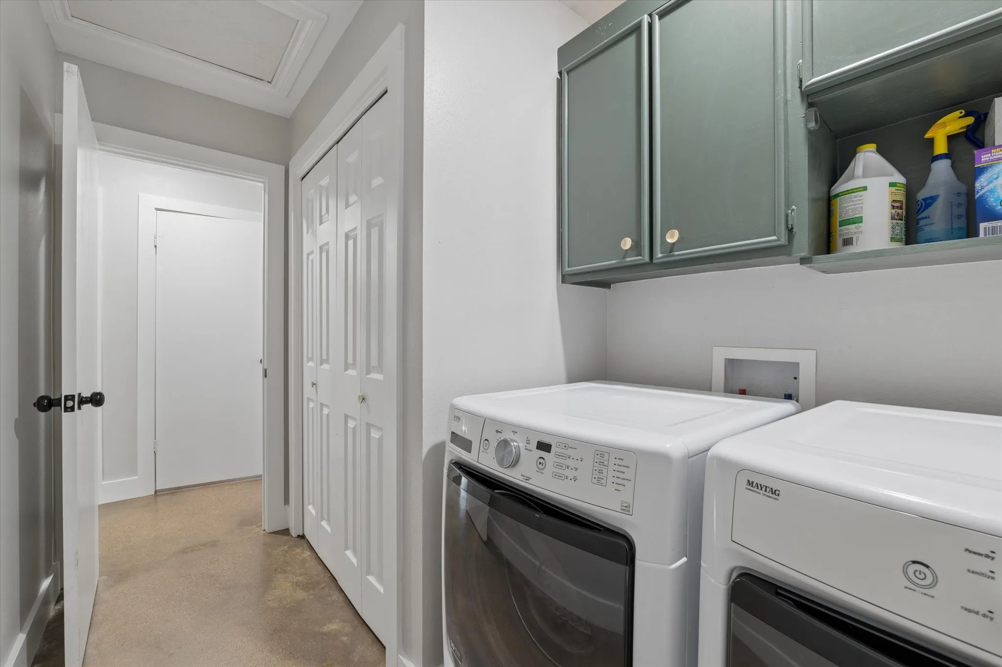 Laundry area featuring built-in cabinetry, upper shelving, and neutral wall paint