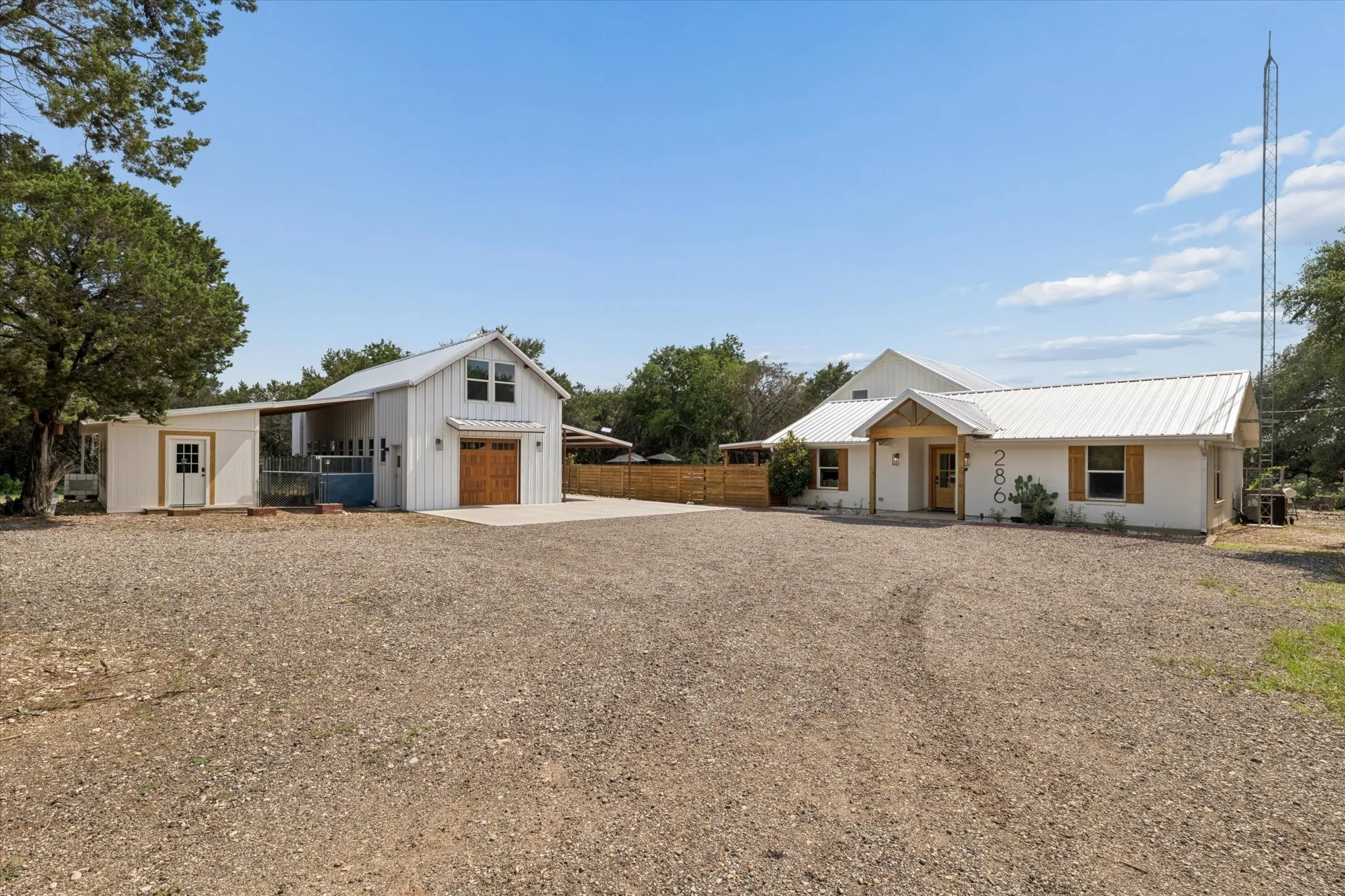 White exterior with metal roofing and an expansive gravel driveway