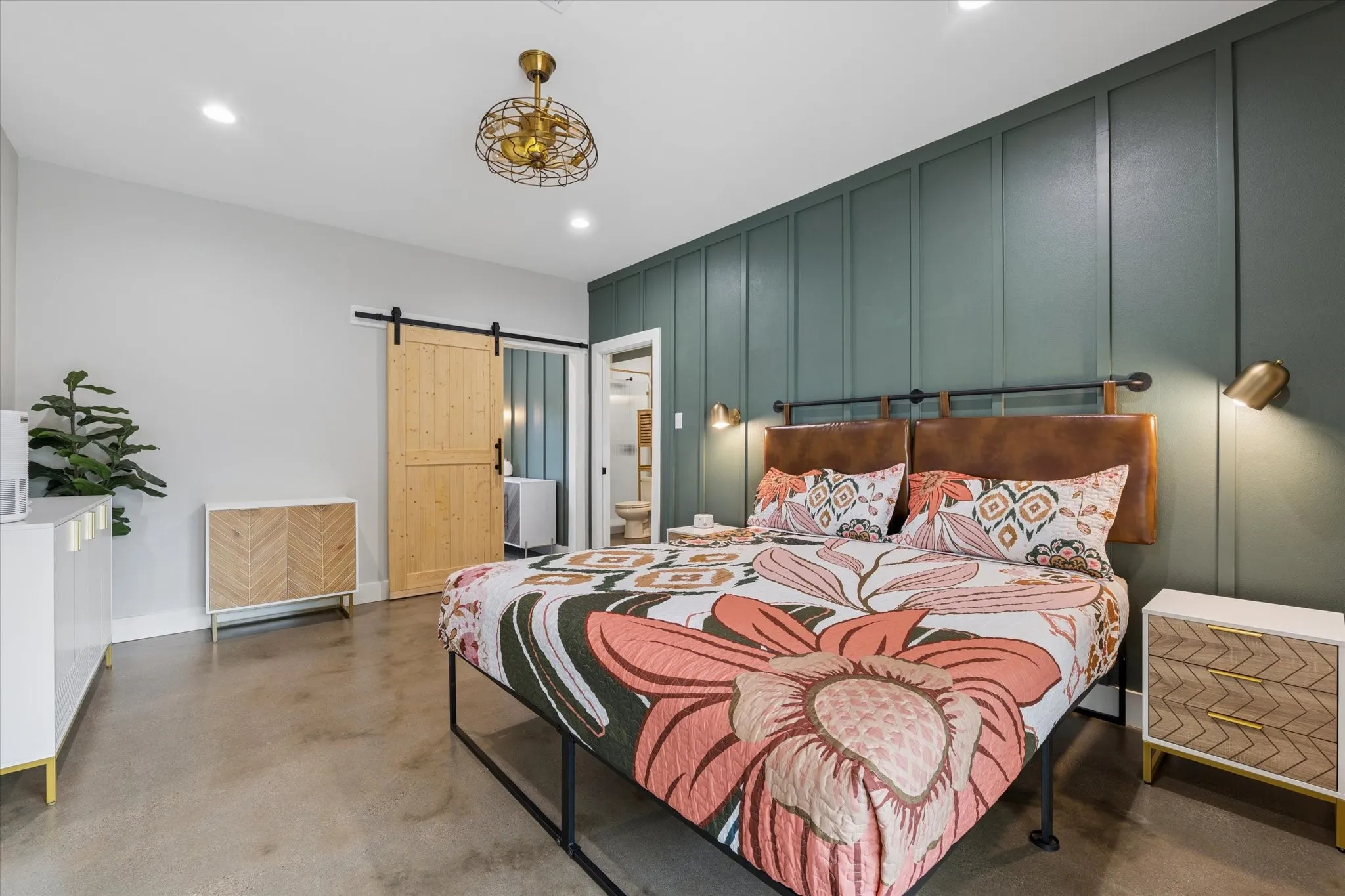 Modern bedroom featuring a paneled accent wall, concrete flooring, a natural wood barn door, and recessed lighting