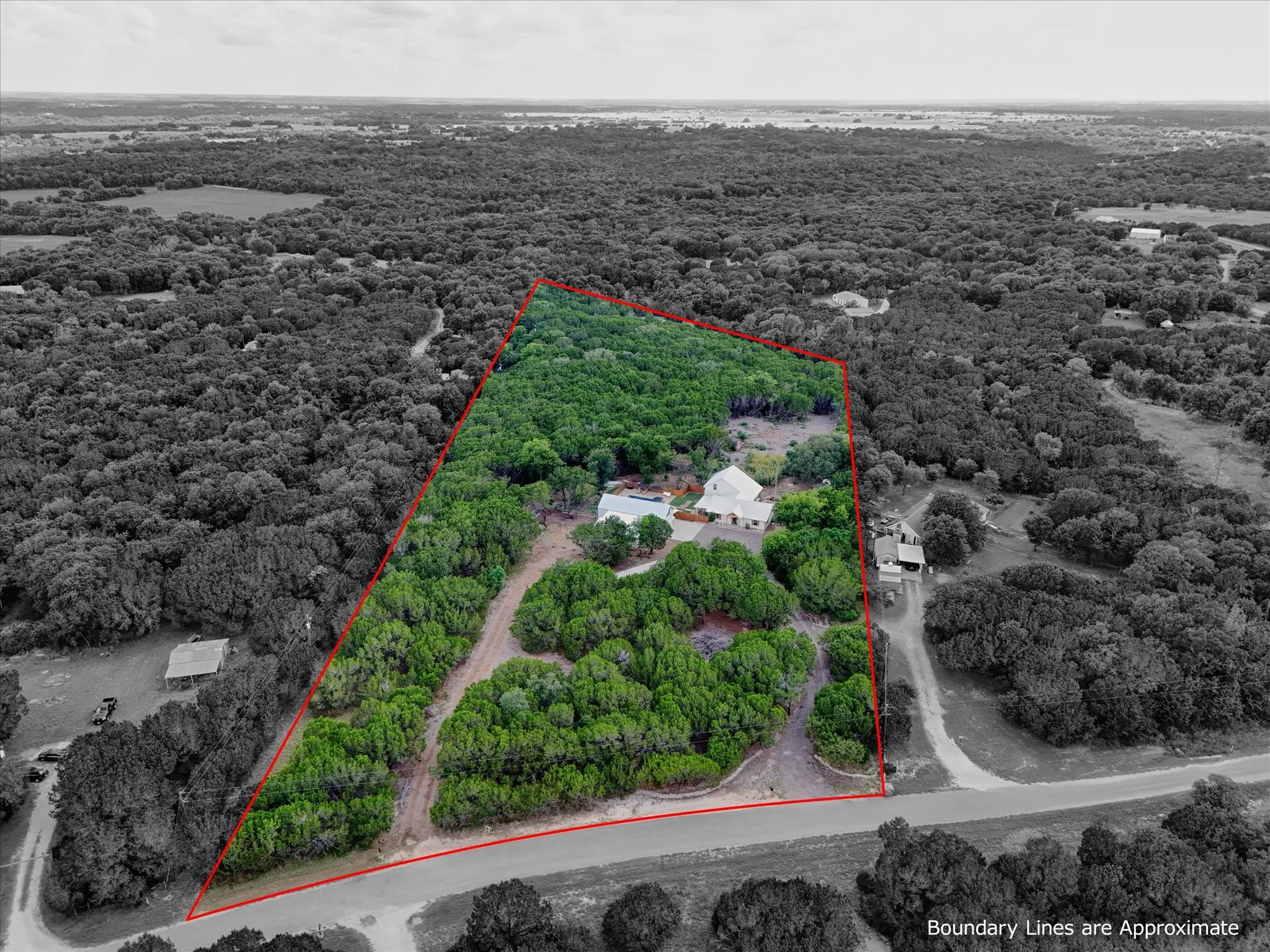 Expansive wooded acreage featuring a main residence and additional structures amidst mature trees