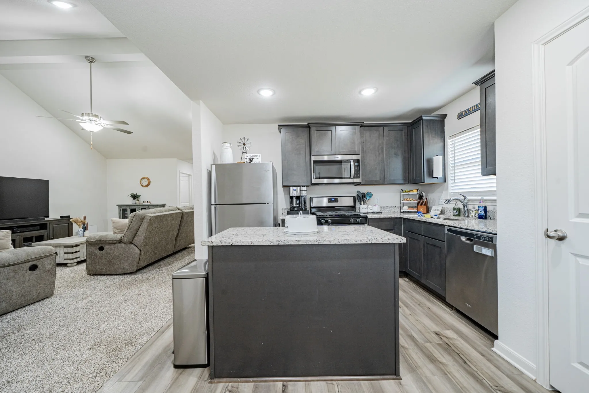 Kitchen featuring dark cabinetry, stainless steel appliances, and a central island with a light-toned countertop