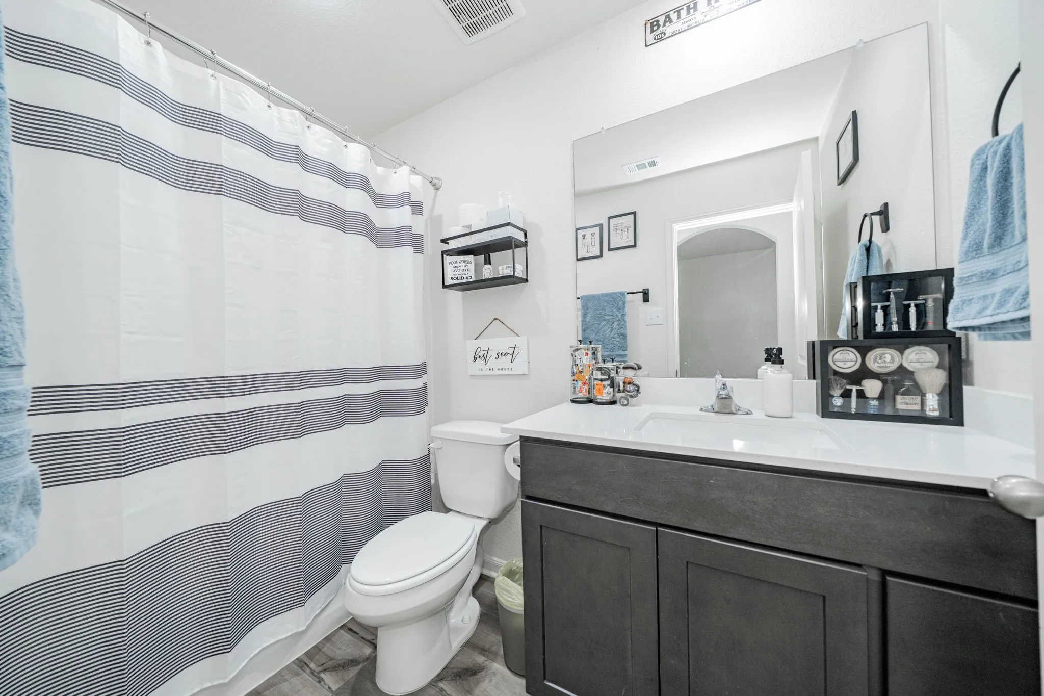 Full bathroom featuring a dark wood-finish vanity with a white countertop, an integrated sink, and a large mirror