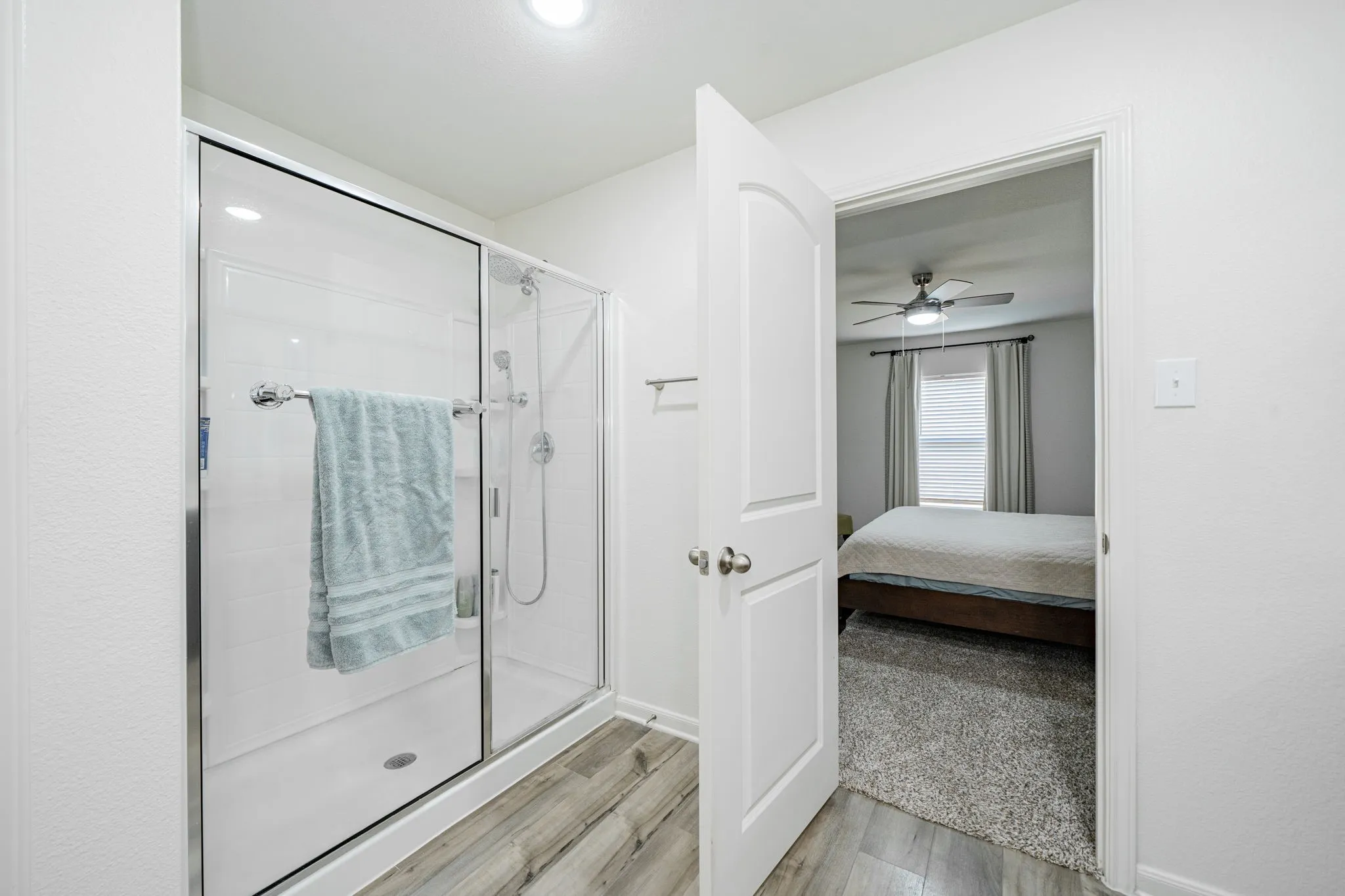 Shower enclosure with a clear glass door, chrome hardware, and a rainfall showerhead