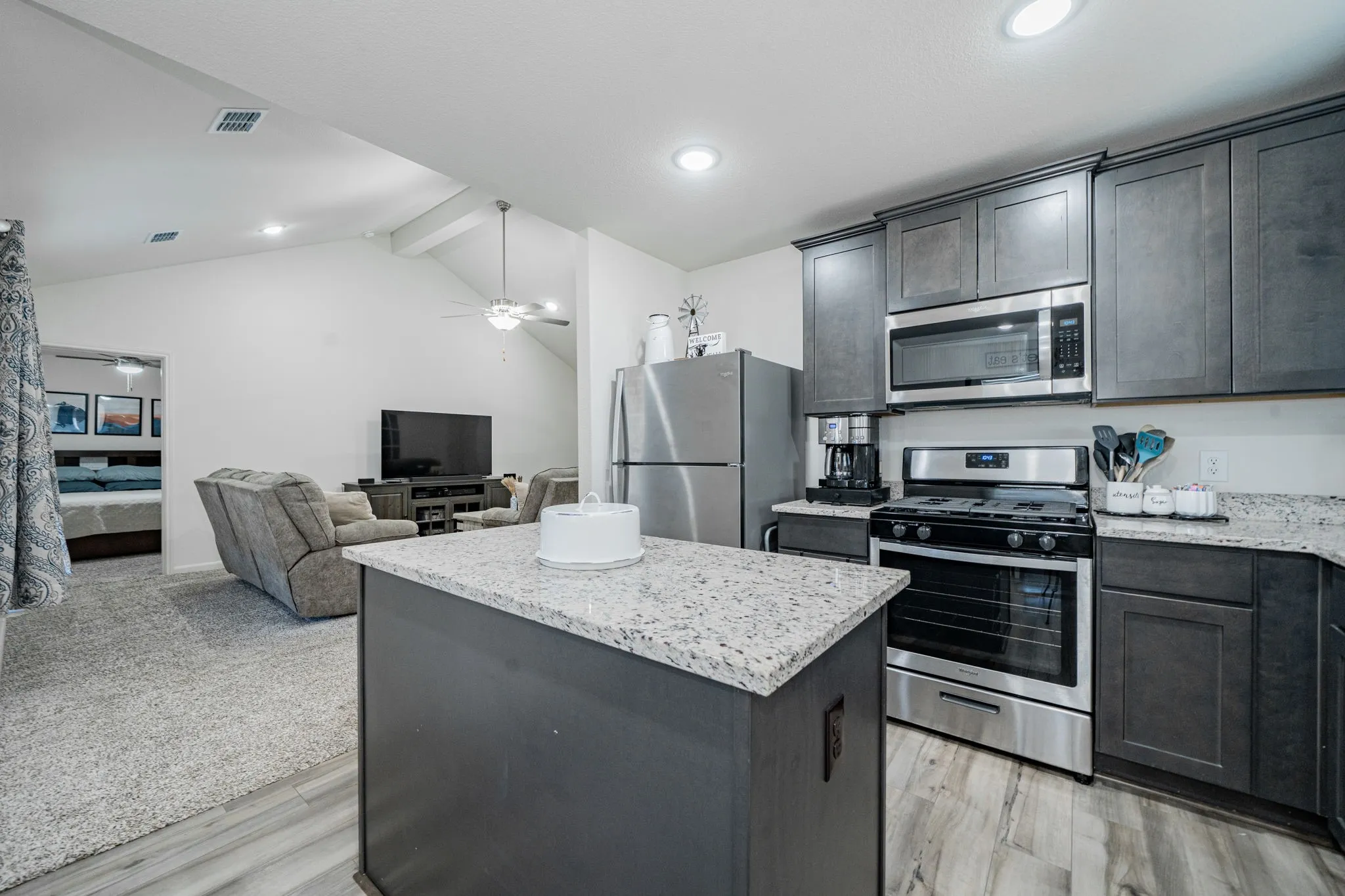 Kitchen featuring dark wood-finish cabinetry, stainless steel appliances, and a central island with granite-style countertops