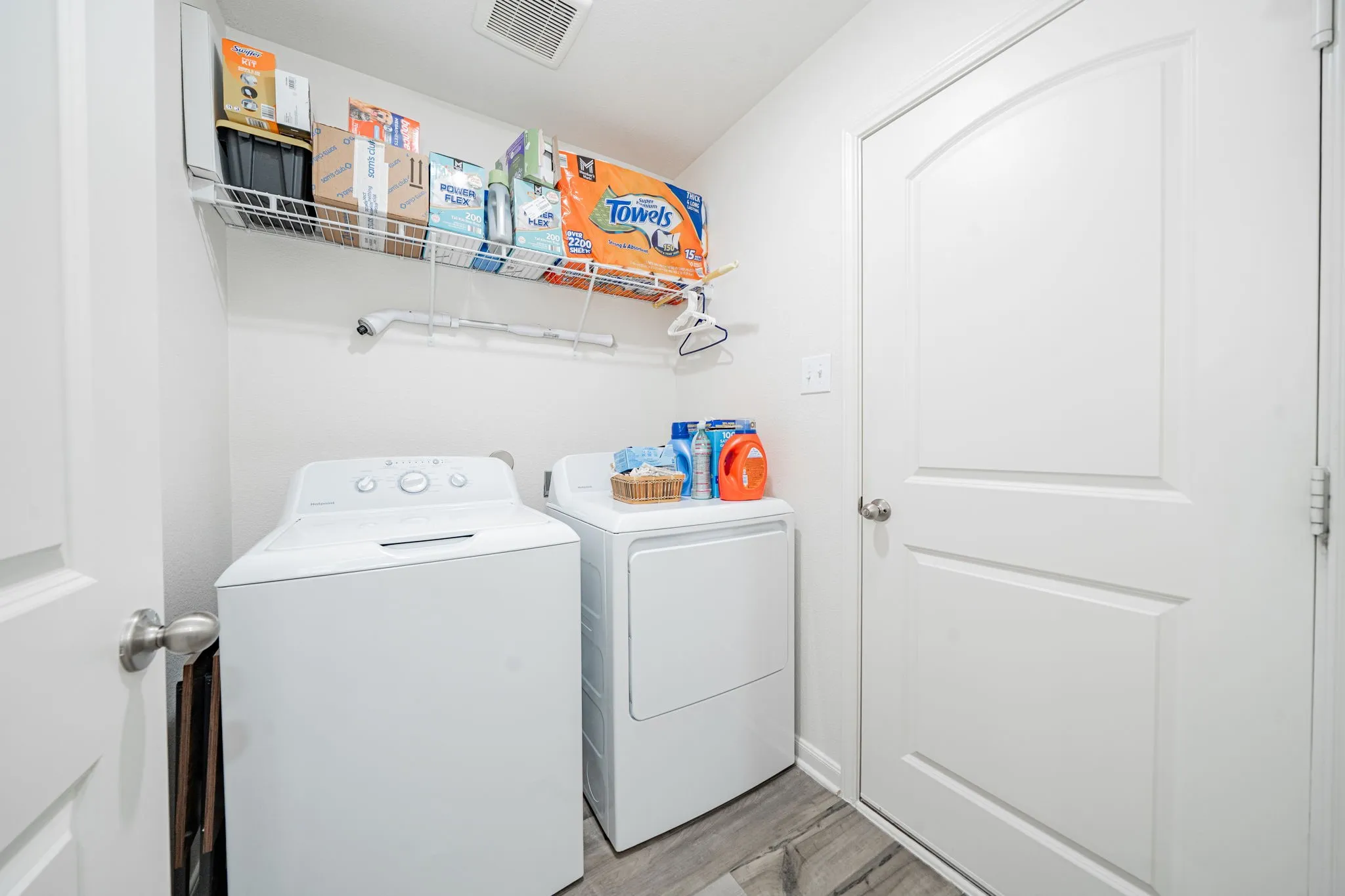 Dedicated laundry area featuring wood-finish flooring, white walls, and a wire shelving unit for storage