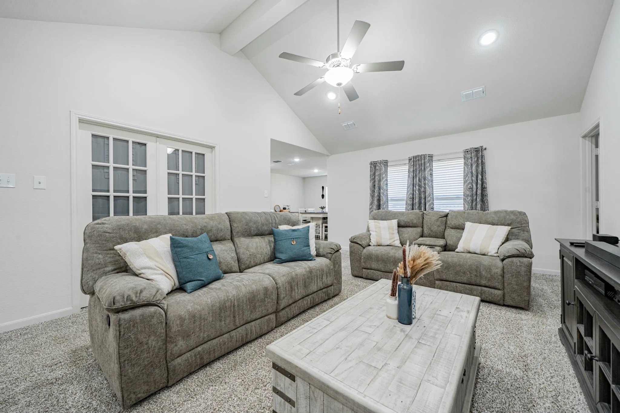 Living space featuring a vaulted ceiling with exposed beam, recessed lighting, and a ceiling fan