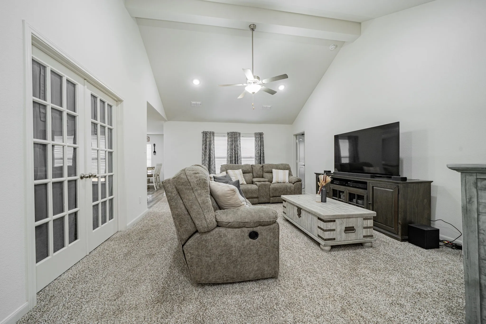 Living area featuring a vaulted ceiling with exposed beams, recessed lighting, and a ceiling fan