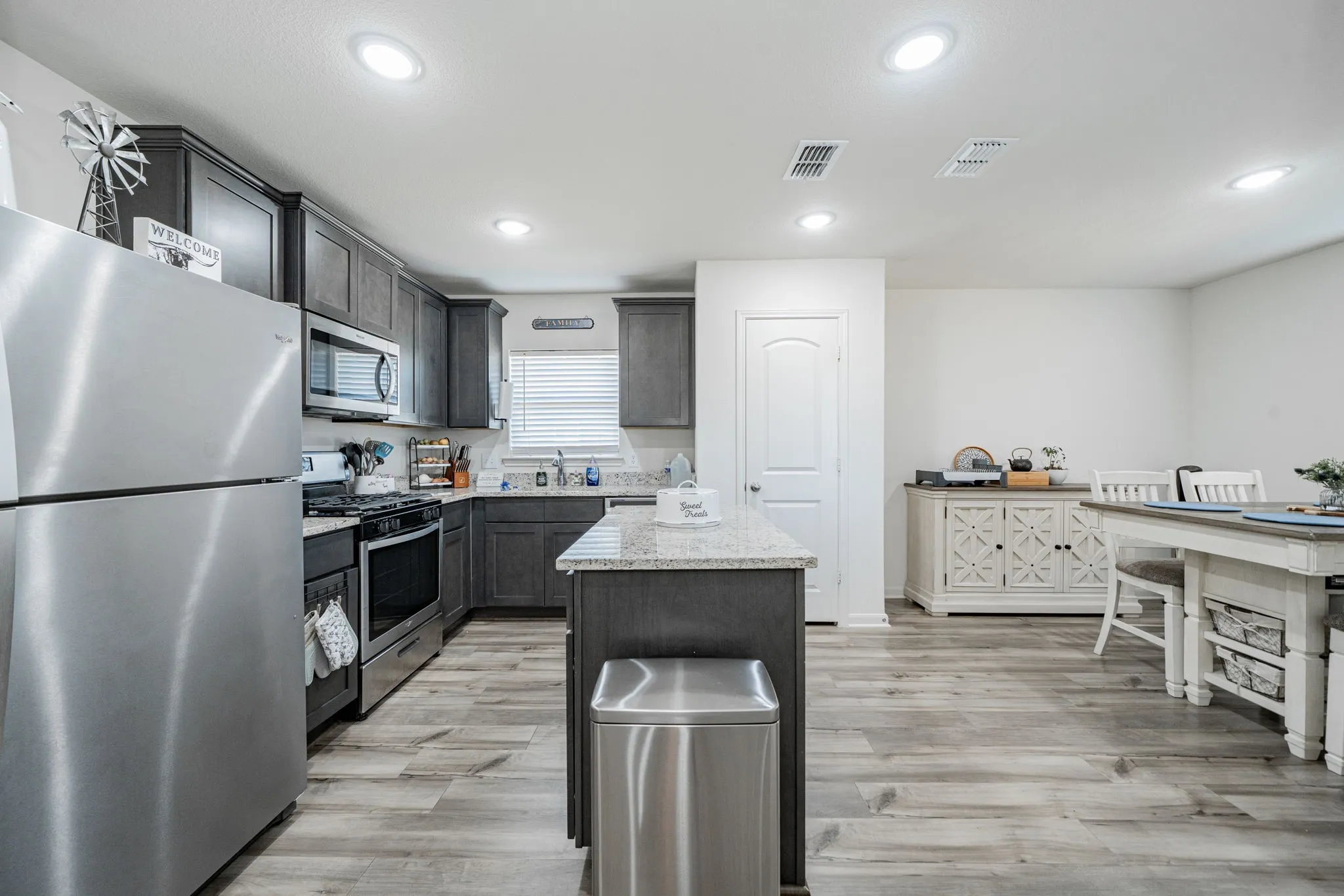 Contemporary kitchen featuring stainless steel appliances, dark wood cabinetry, and light-toned wood-finish flooring
