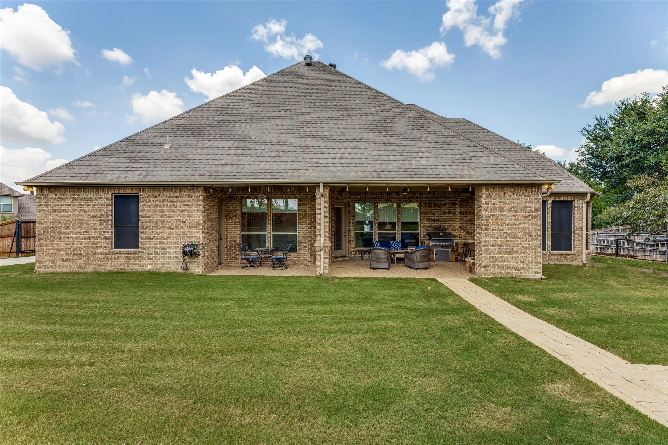 Expansive backyard featuring a brick exterior and a covered patio