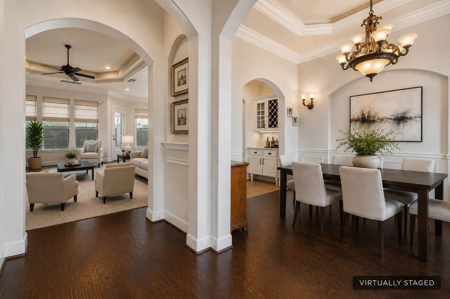 Dark wood-finish flooring throughout, tray ceiling with crown molding, and an elegant chandelier