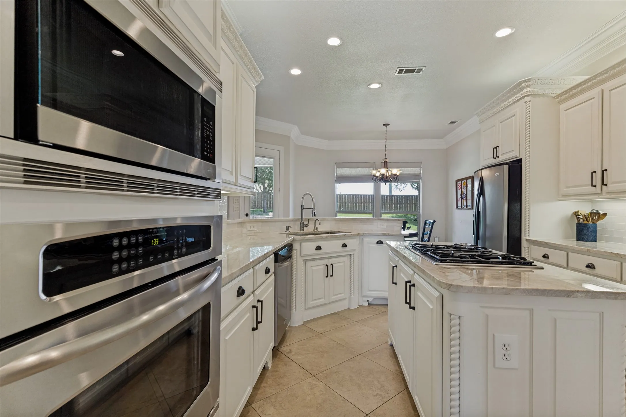 Modern kitchen featuring white cabinetry, stainless steel appliances, recessed lighting, and a kitchen island with a gas cooktop