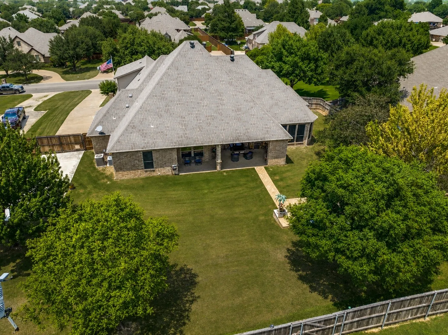 Brick exterior residence with an expansive rear lawn, mature landscaping, and a covered back patio
