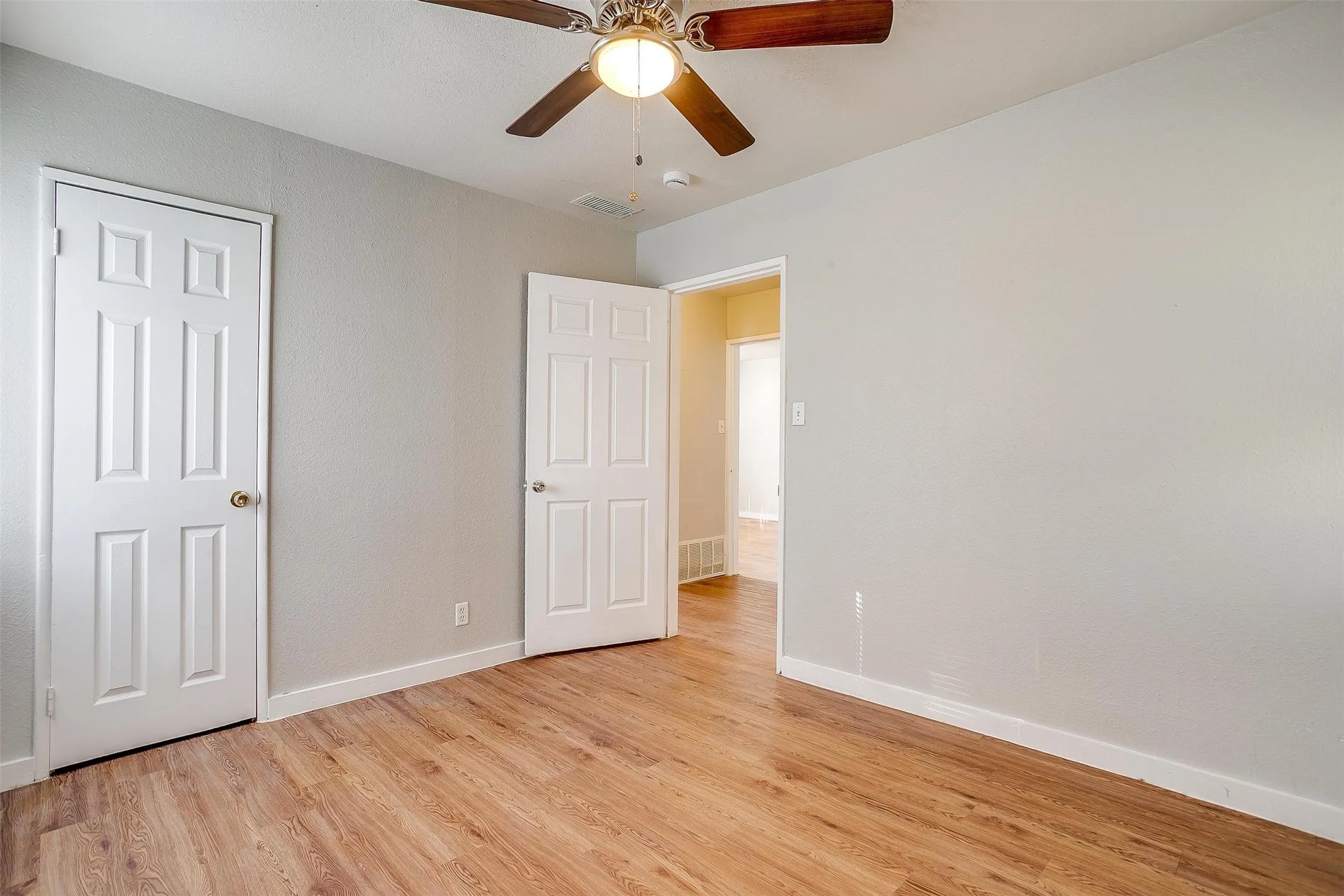 Interior room featuring wood-finish flooring, light gray walls, and white trim