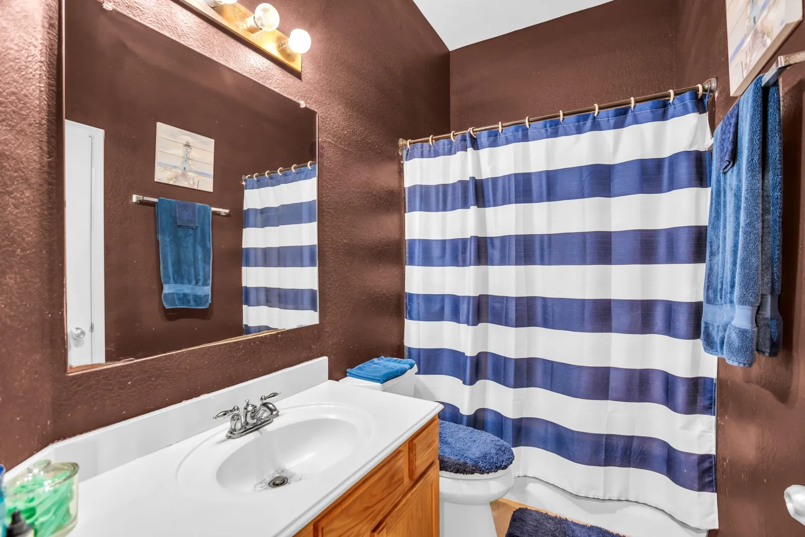 Bathroom featuring a single vanity with wood-finish cabinetry, a white countertop, and an integrated sink