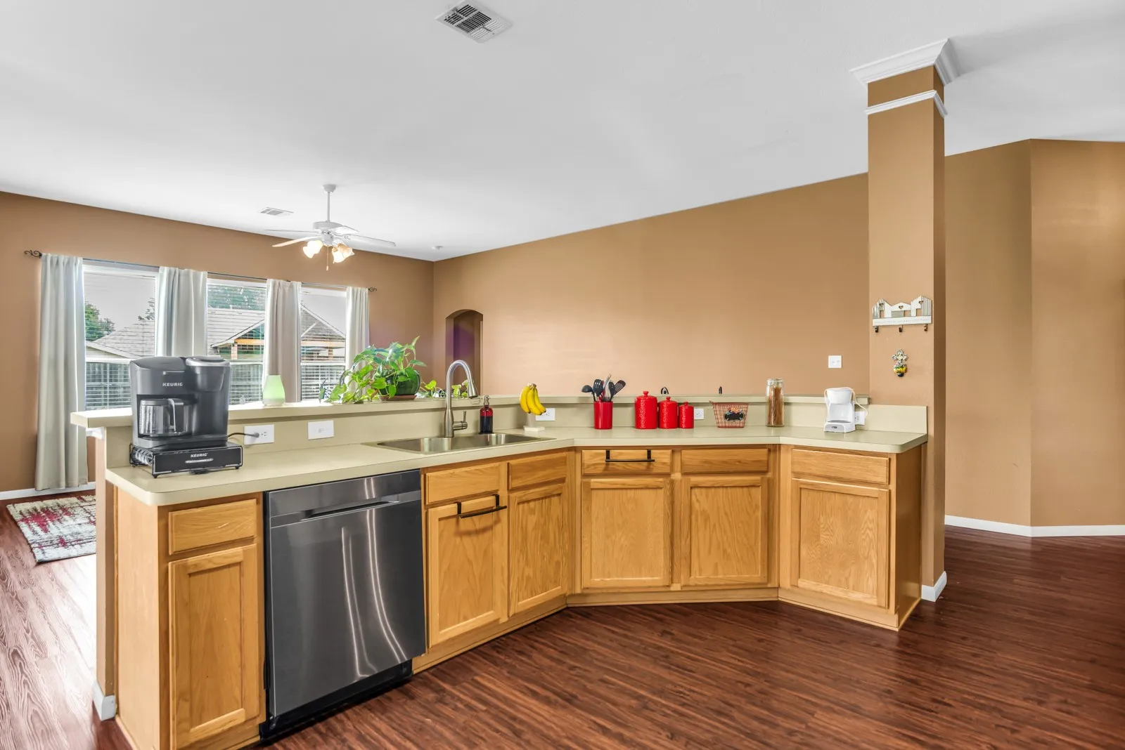 Kitchen featuring wood-finish flooring, light wood cabinetry, a stainless steel dishwasher, and a double basin sink