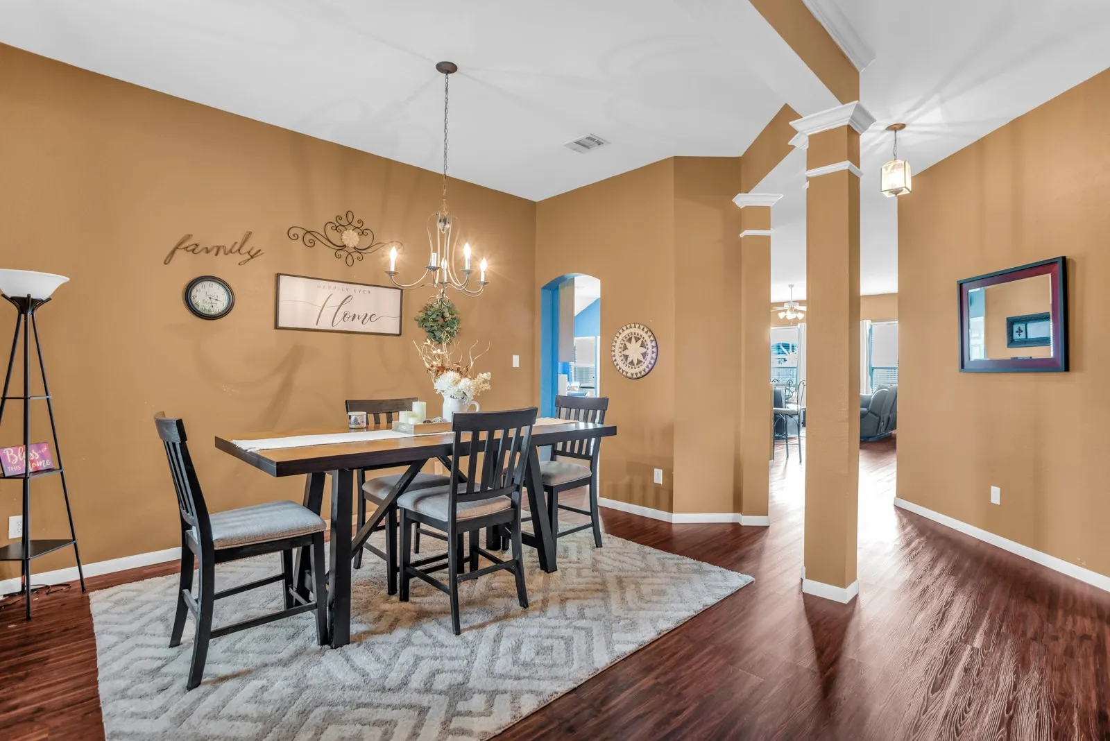 Dining area featuring rich wood-finish flooring, a contemporary chandelier, and a decorative archway