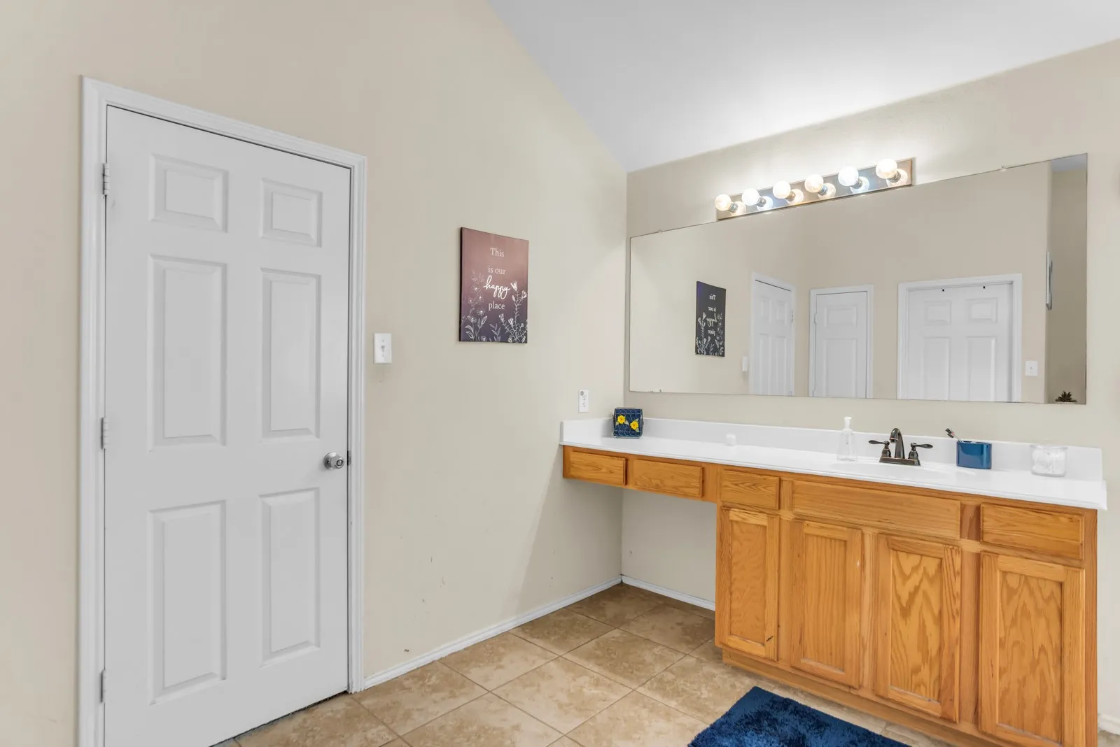 Bathroom vanity featuring wood cabinetry, white countertop, and expansive wall-mounted mirror
