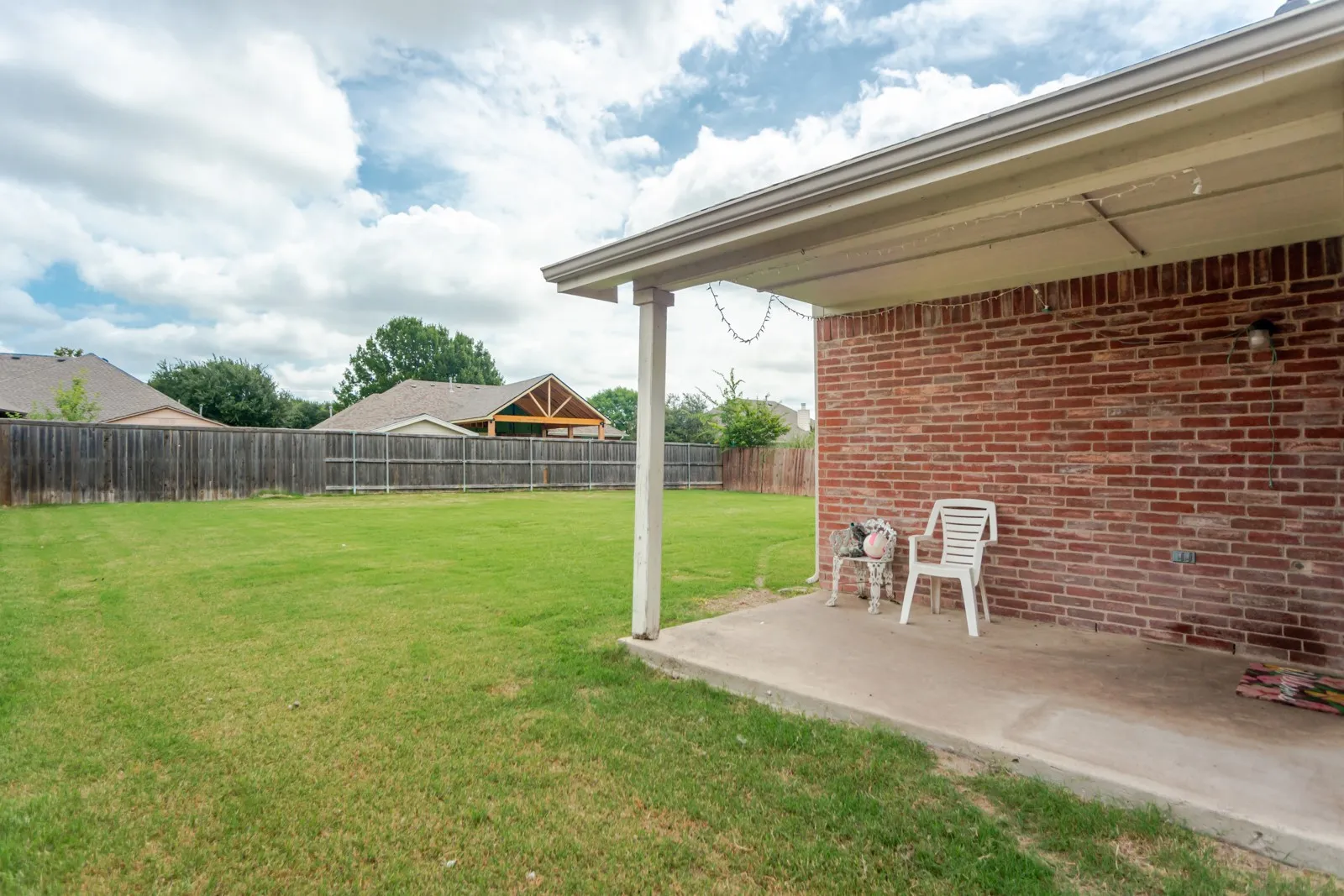 Expansive backyard with a full privacy fence and a covered patio